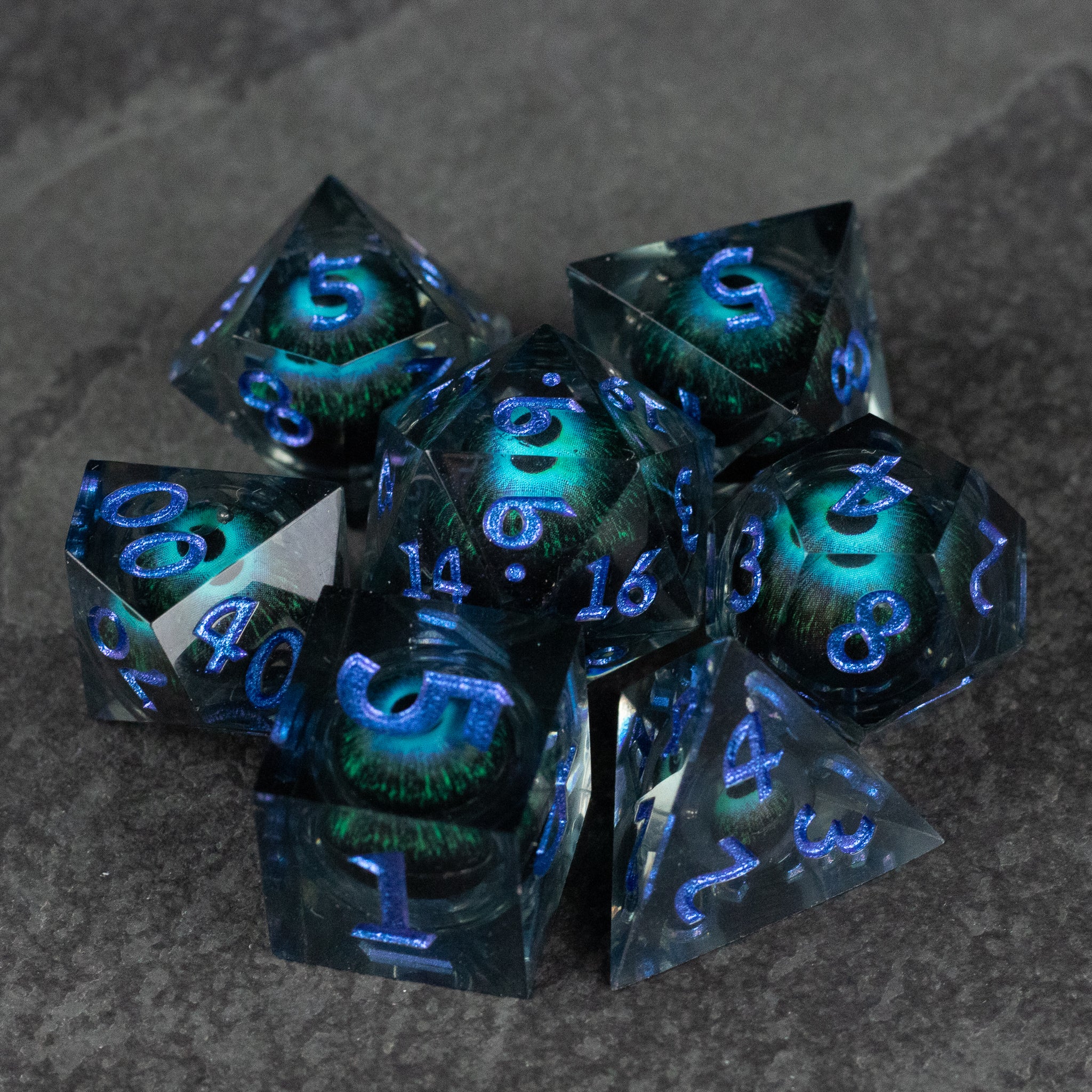 Blue Beholder's Eye Dice Set - Blue transparent polyhedral dice set with glowing blue core and sharp edges on dark surface.
