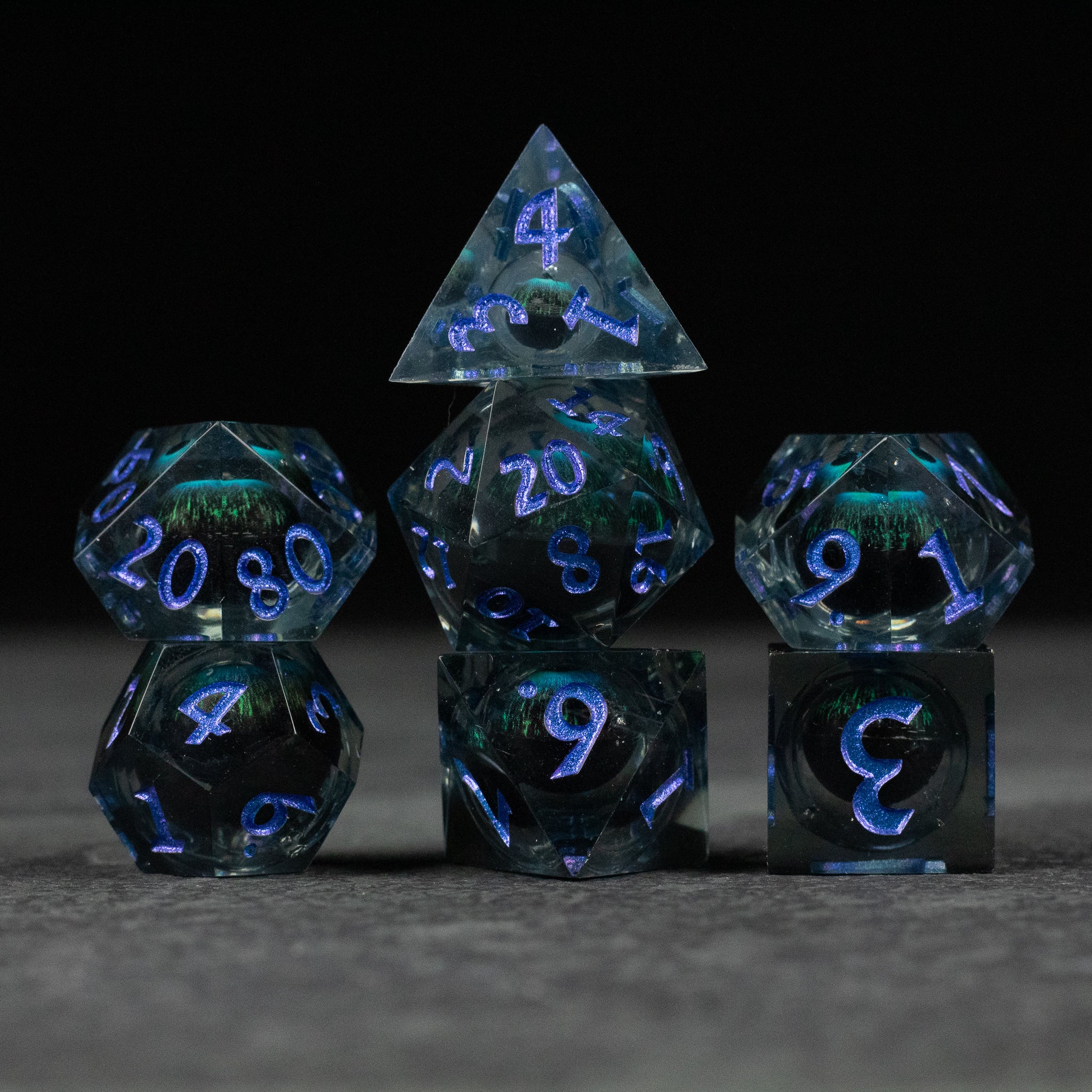 Blue Beholder's Eye Dice Set - Blue transparent polyhedral dice set with sharp edges and glowing blue numbers, liquid core effect.