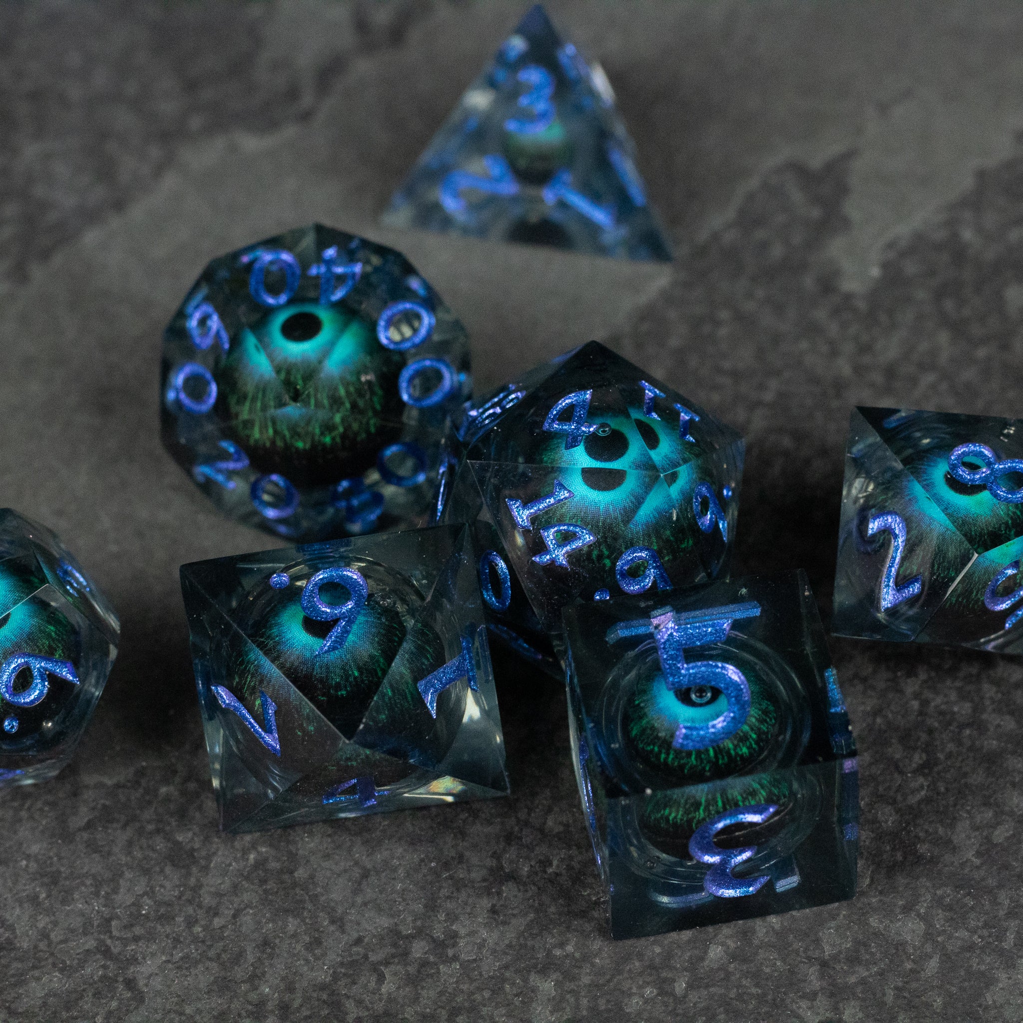 Blue Beholder's Eye Dice Set - Blue translucent sharp-edged dice set with swirling liquid core and glowing blue numbers.