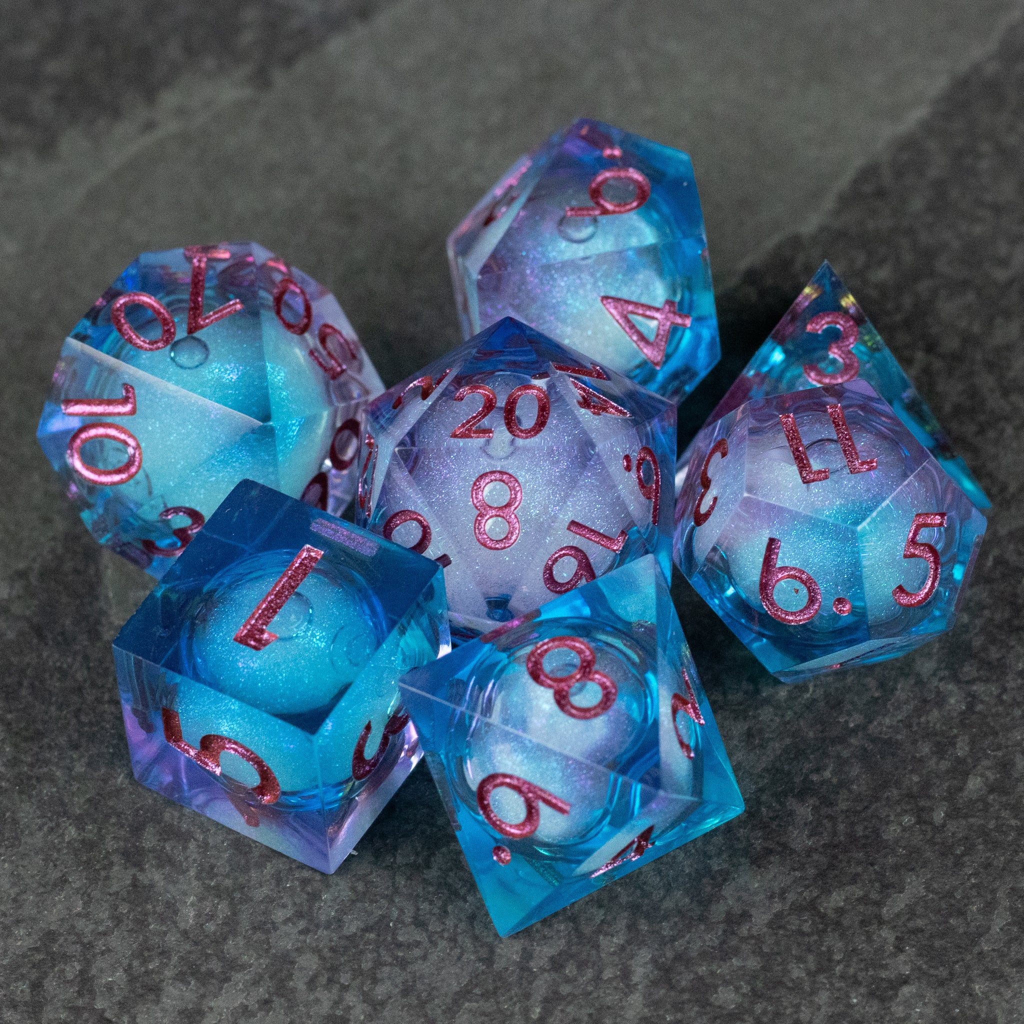 Crystallomancy Dice Set - Translucent blue polyhedral dice set with red numbers and sharp edges, featuring a liquid core effect.