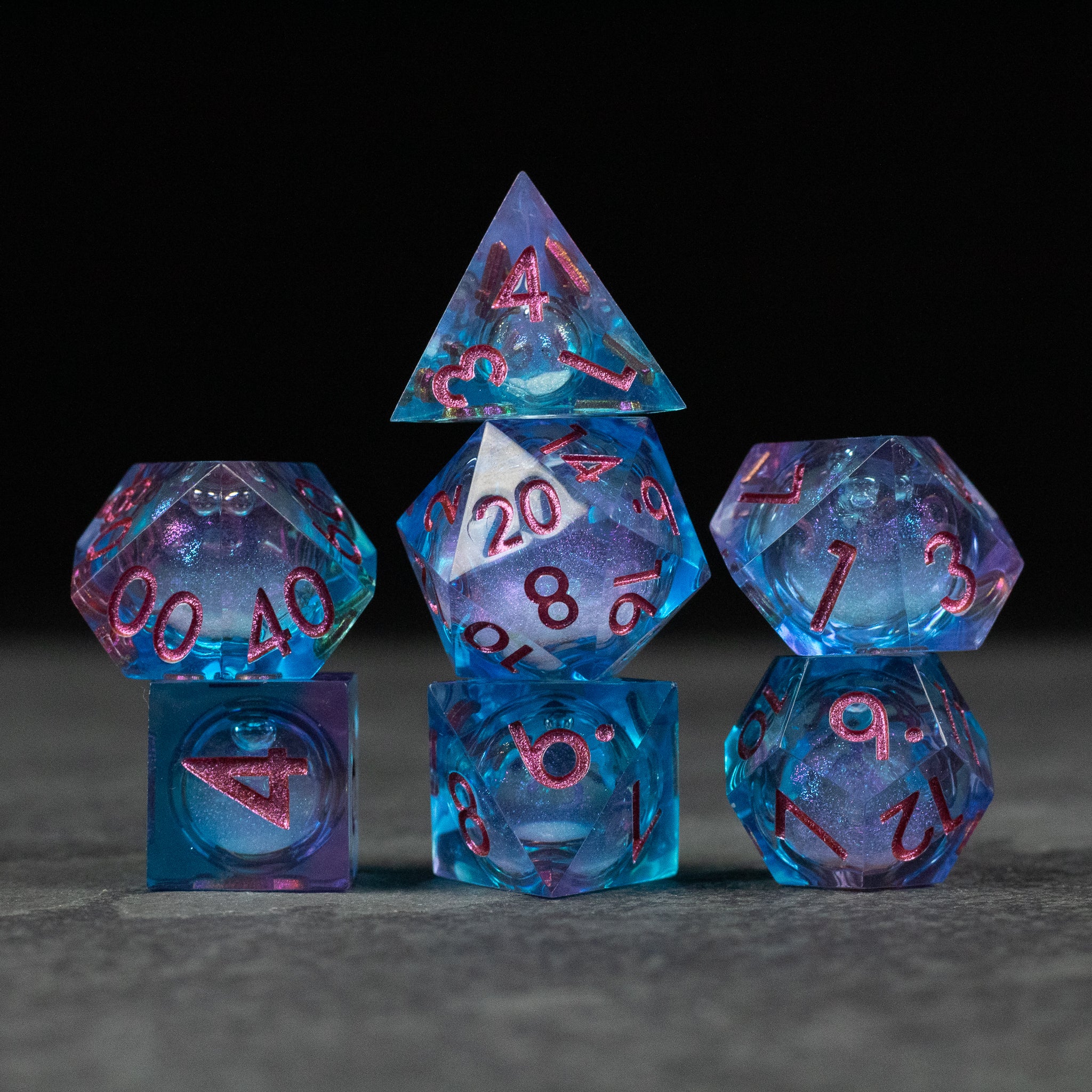 Crystallomancy Dice Set - Blue translucent polyhedral dice set with red numbers and a liquid core, including d4, d6, d8, d10, d12, and d20 shapes.