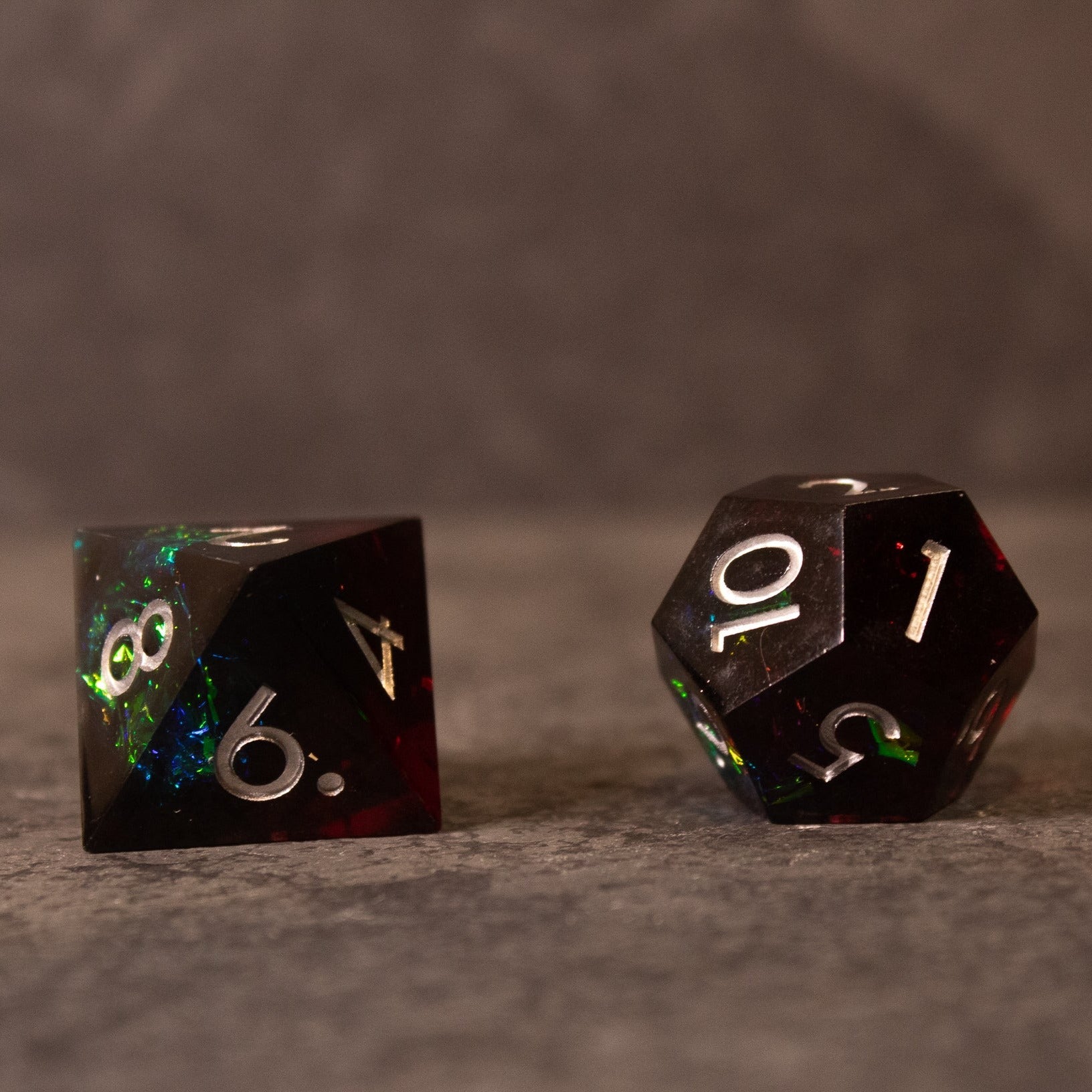 Blood Magic - Sharp Edge Opalescent Dice - Two sharp-edged black opalescent dice with white numbering, showing numbers 6, 4, 10, and 1.