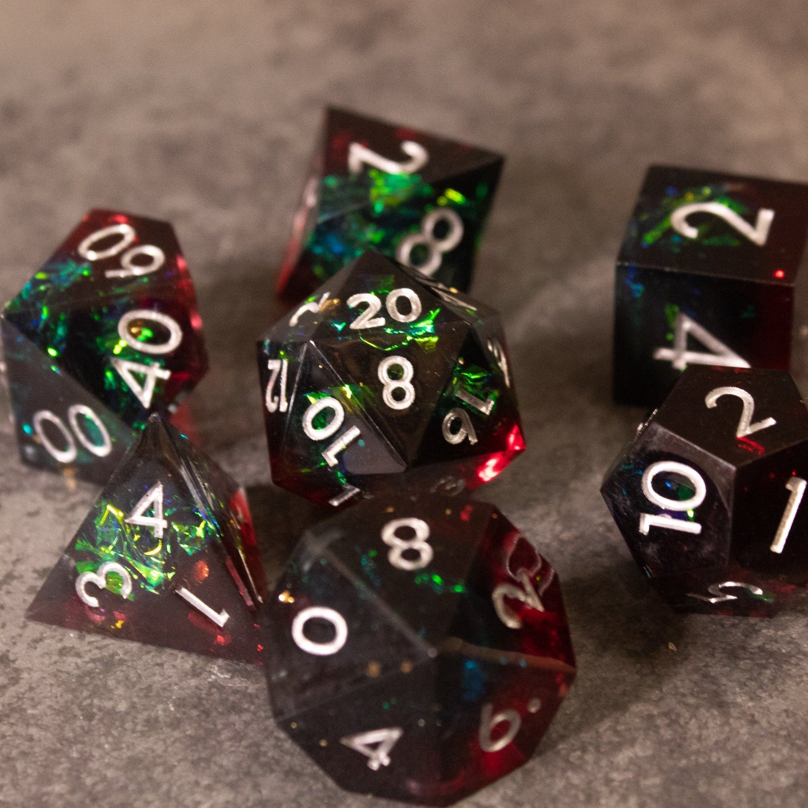 Blood Magic - Sharp Edge Opalescent Dice - Set of sharp-edged polyhedral dice with a translucent red and green opalescent finish and white numbering.
