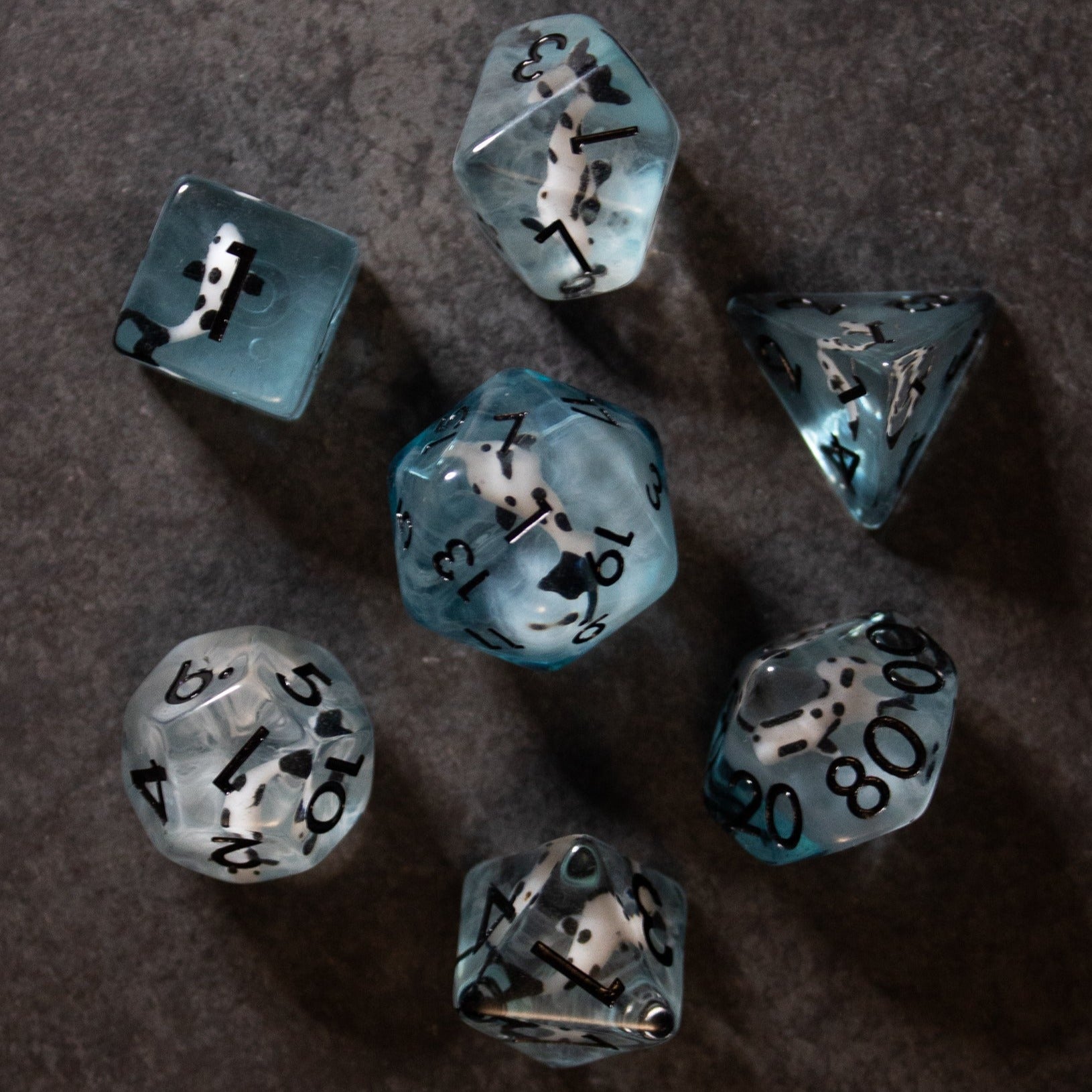 Black Koi & Steel Blue Dice - Seven polyhedral dice in smoky steel blue with embedded black koi fish inclusions and black numbers.