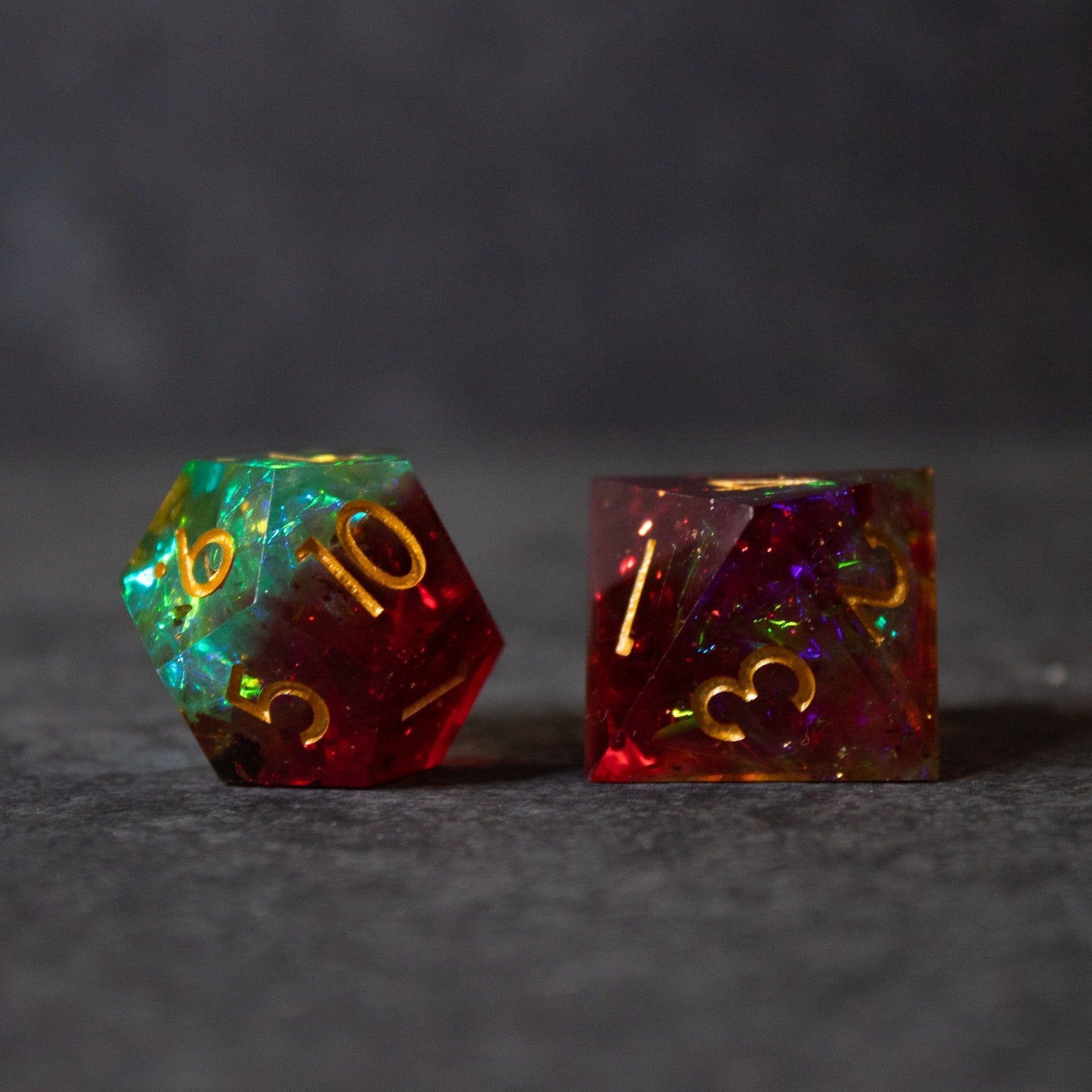Fairy Fire - Sharp Edge Opalescent Dice - Two sharp-edged polyhedral dice with fiery red and green opalescent colors and gold numbering.