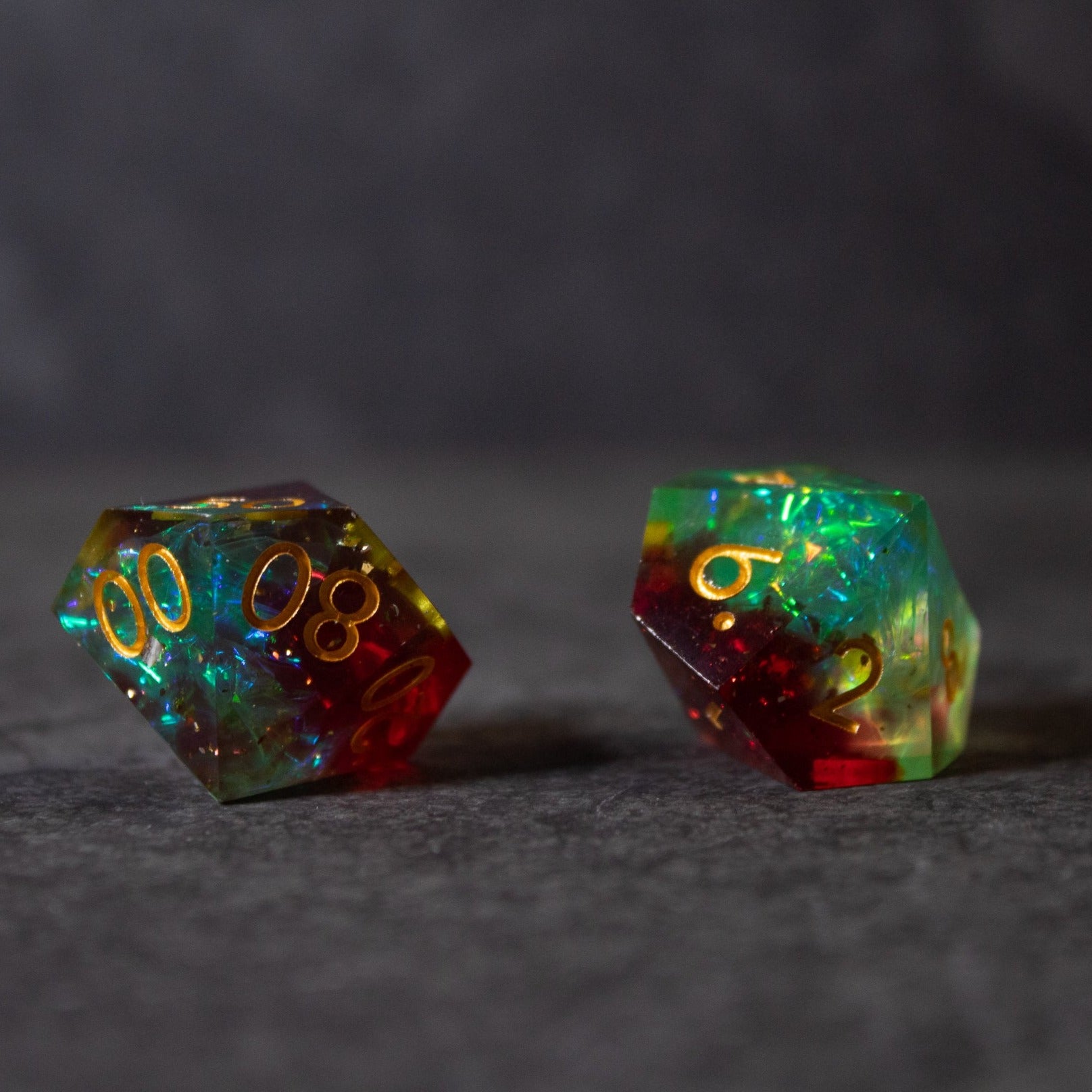 Fairy Fire - Sharp Edge Opalescent Dice - Two sharp-edged, opalescent dice with swirling red, green, and blue hues and gold numbers.