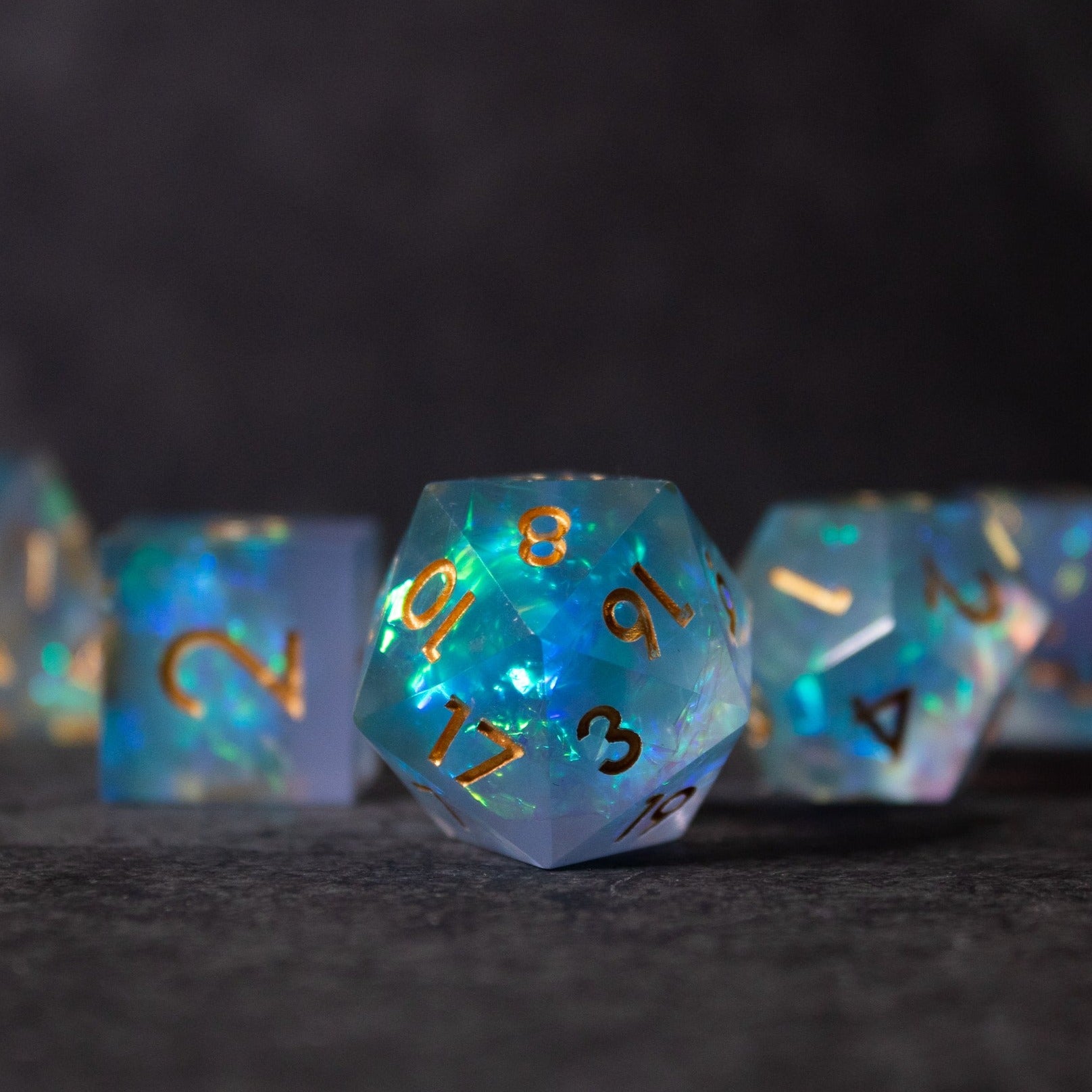 Frost Fire - Sharp Edge Opalescent Dice - Blue opalescent sharp edge 20-sided dice with gold and black numbering on dark surface.