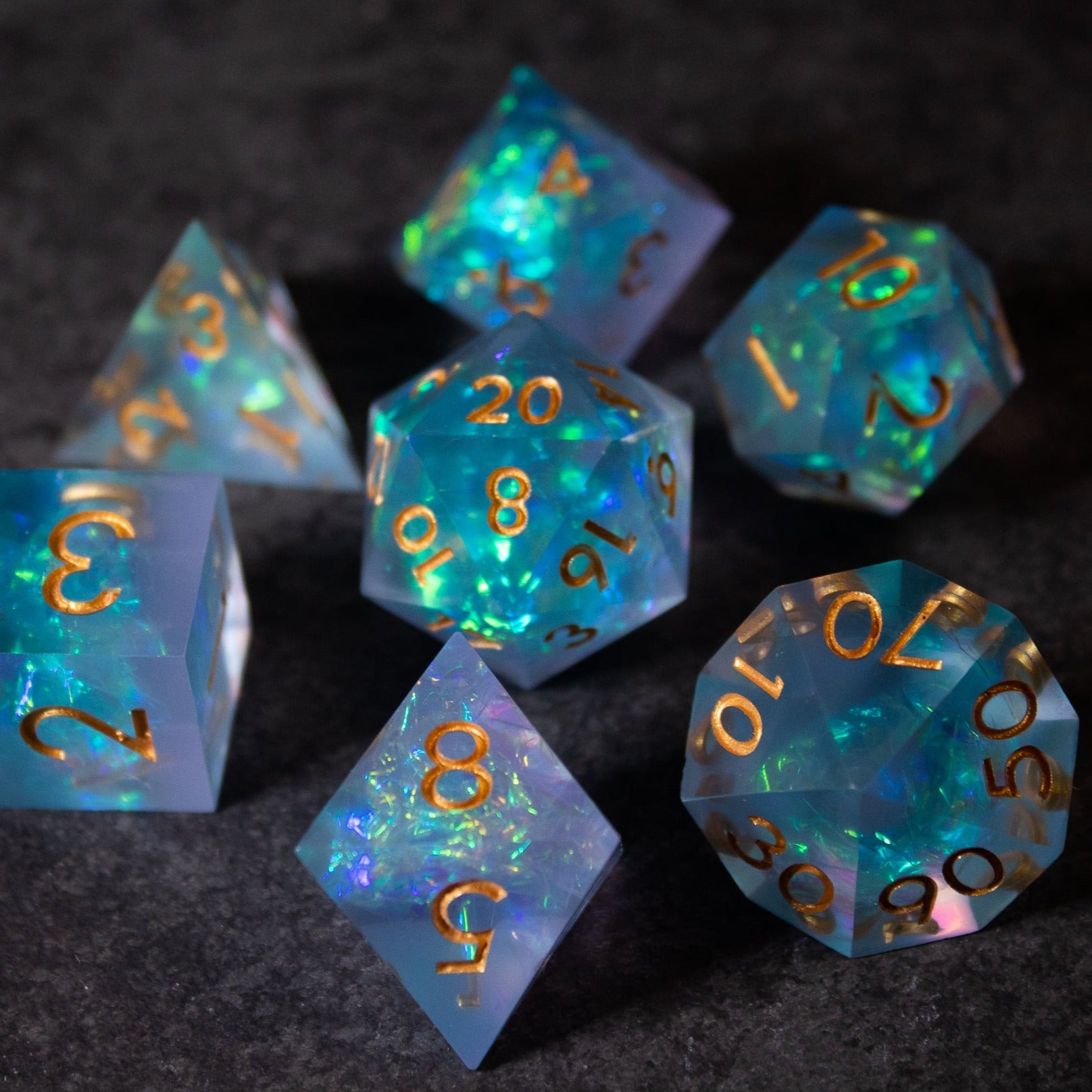 Frost Fire - Sharp Edge Opalescent Dice - Set of seven sharp-edged opalescent dice in icy blue with gold numerals and shimmering iridescent inclusions.