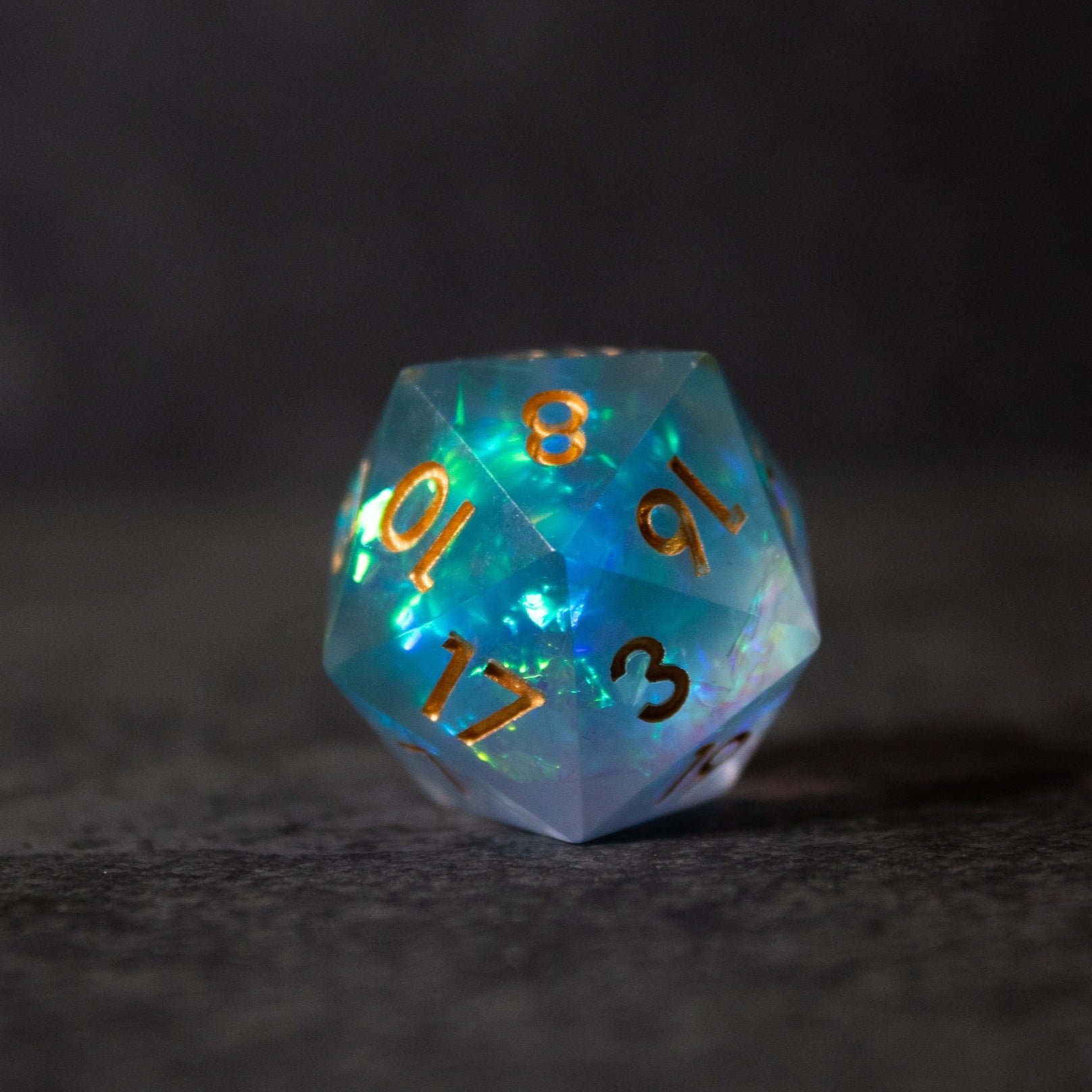 Frost Fire - Sharp Edge Opalescent Dice - Blue-green opalescent 20-sided die with sharp edges and gold numbering.