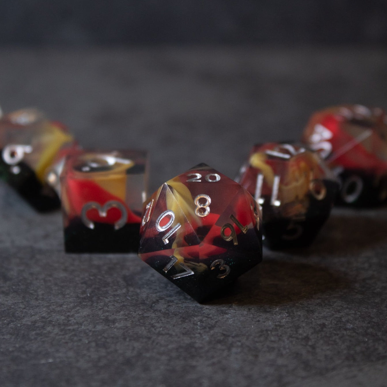 Widowgast's Flame - Sharp Edge Dice - Set of polyhedral dice with sharp edges, featuring red, black, and gold swirling colors and white numbering.