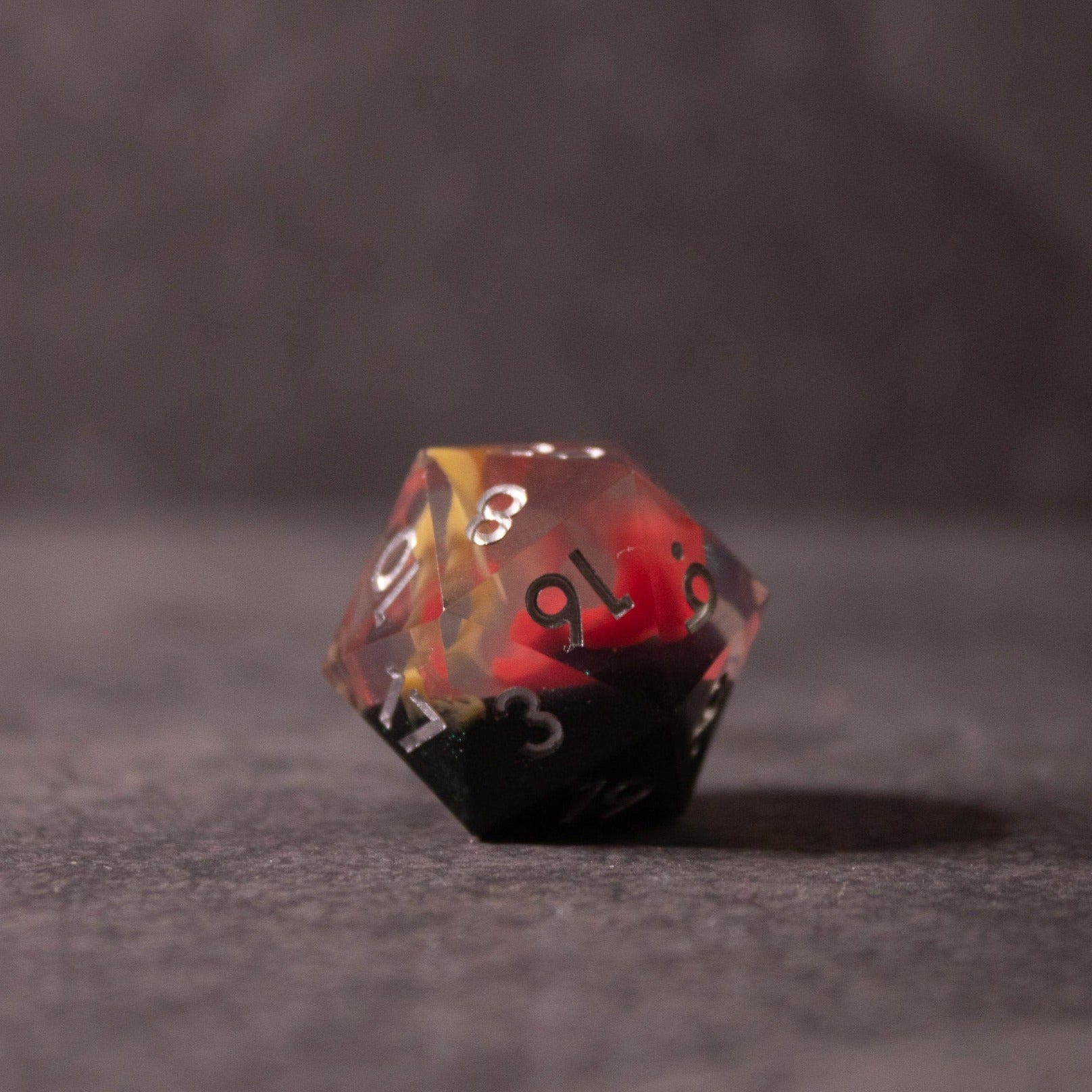 Widowgast's Flame - Sharp Edge Dice - Twenty-sided dice with sharp edges featuring a red, black, and yellow flame-like swirl design and white numbering.