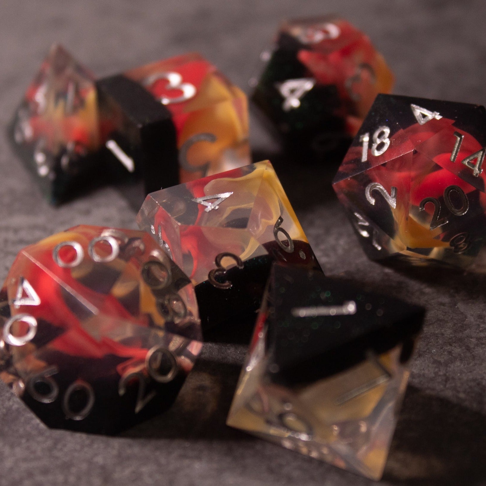 Widowgast's Flame - Sharp Edge Dice - Multi-faceted sharp-edged gaming dice set with fiery red, orange, and black translucent colors and white numerals.