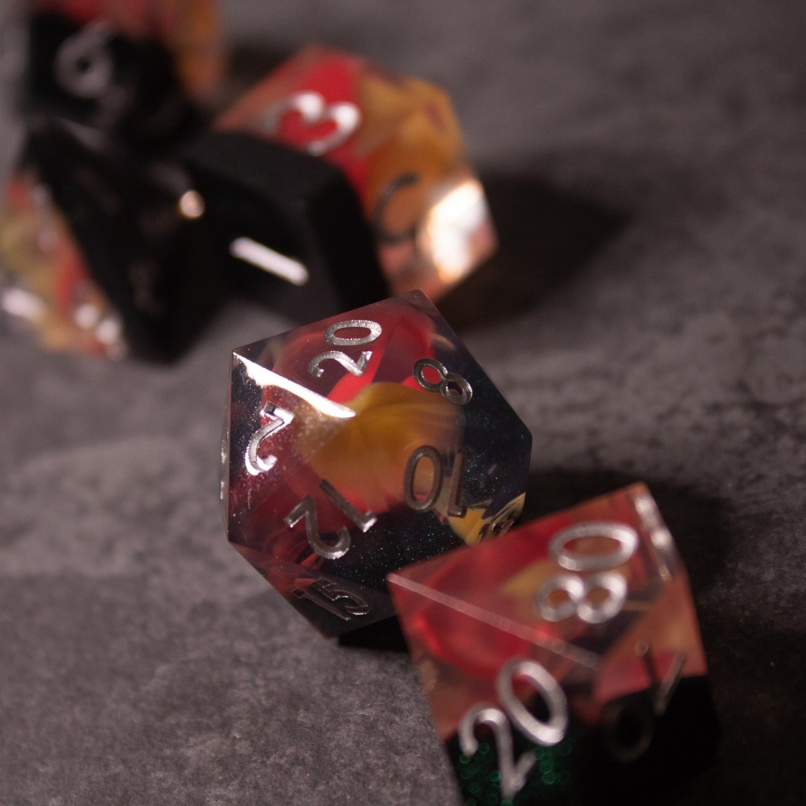 Widowgast's Flame - Sharp Edge Dice - Set of multi-sided polyhedral dice with sharp edges, featuring a fiery red, orange, and black swirl color scheme and white.