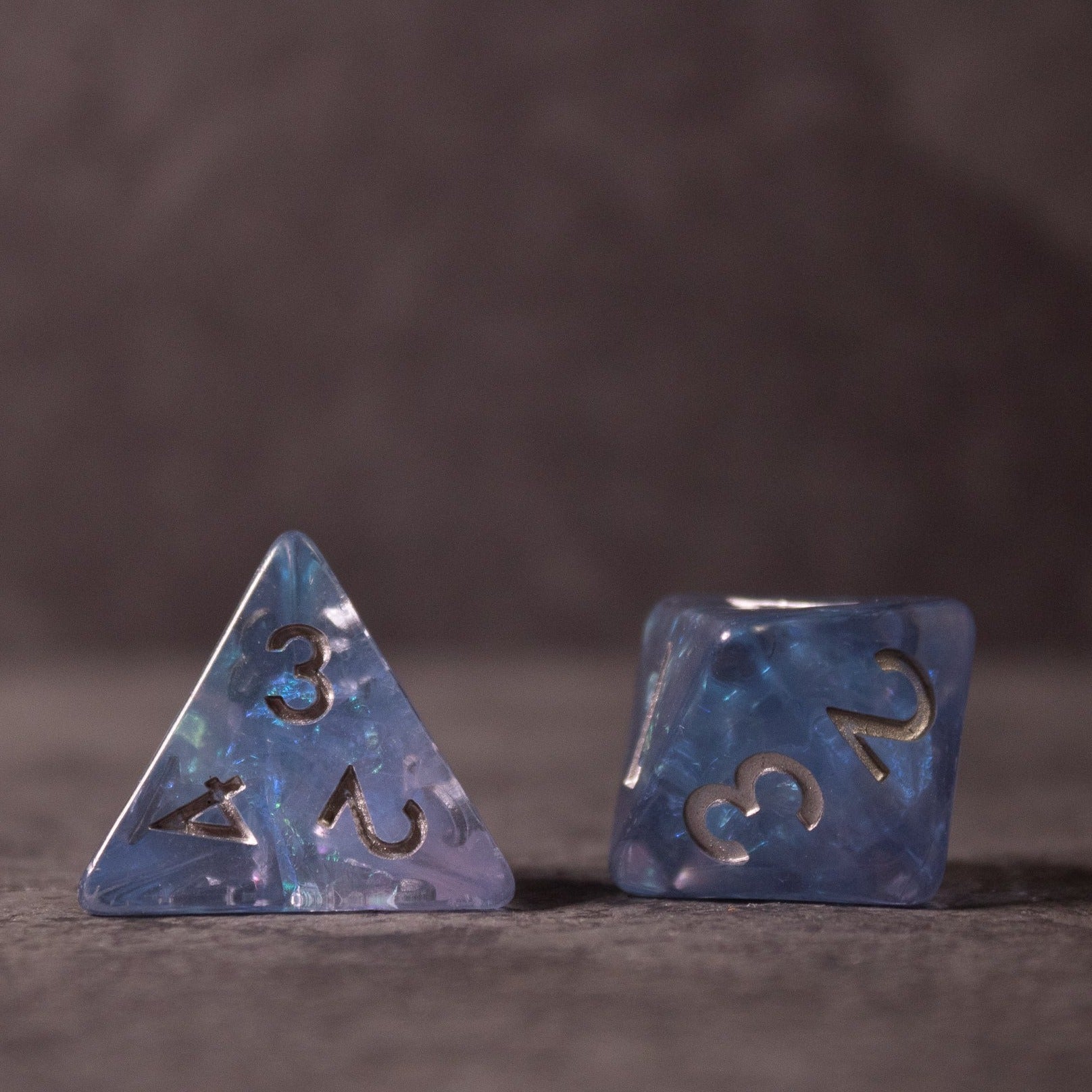 Glacier Ice Dice Set - Blue iridescent resin dice set with 4-sided and 6-sided pieces, featuring gold numbers and internal inclusions.