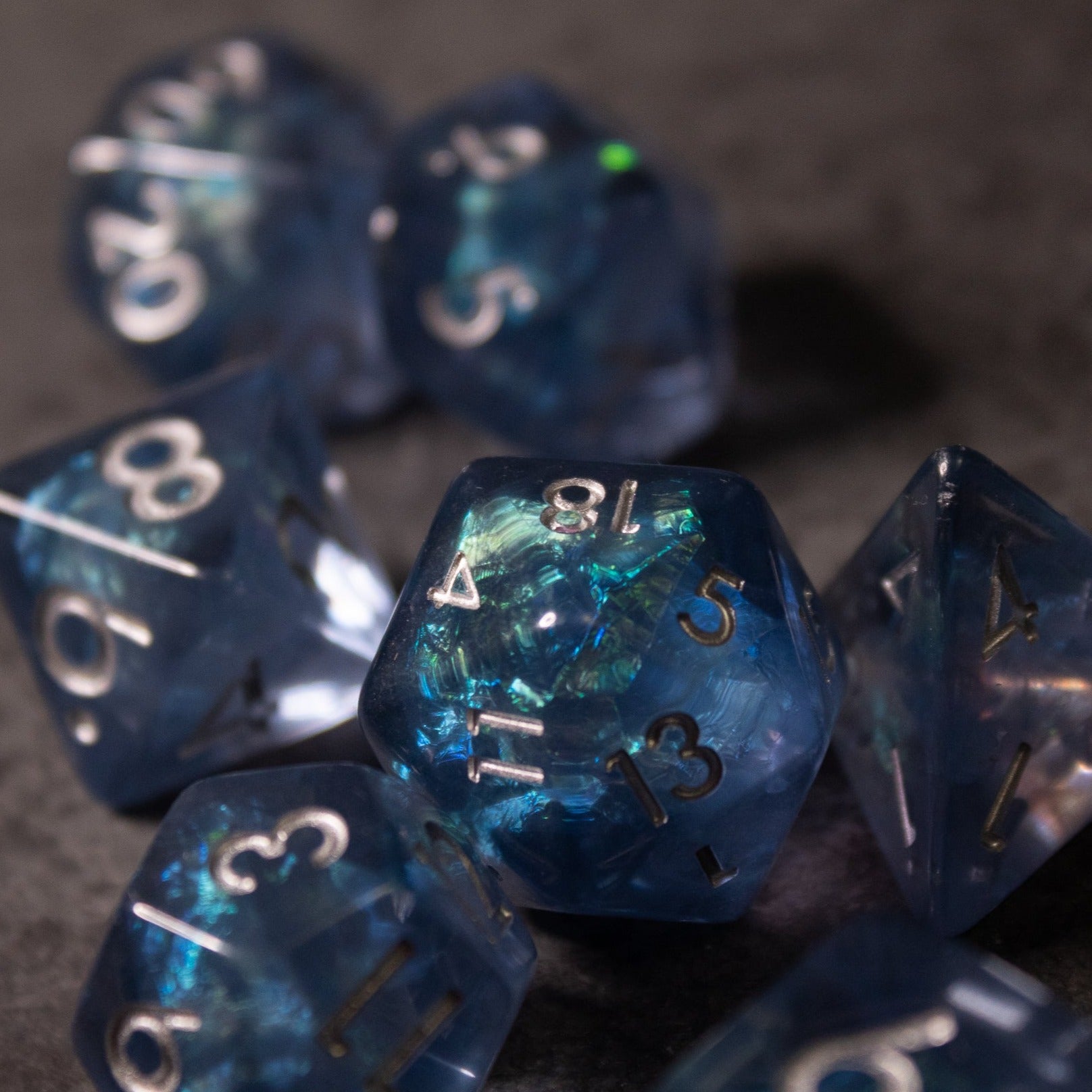 Glacier Ice Dice Set - Set of blue iridescent polyhedral dice with shimmering glacier-like inclusions and silver numbers.
