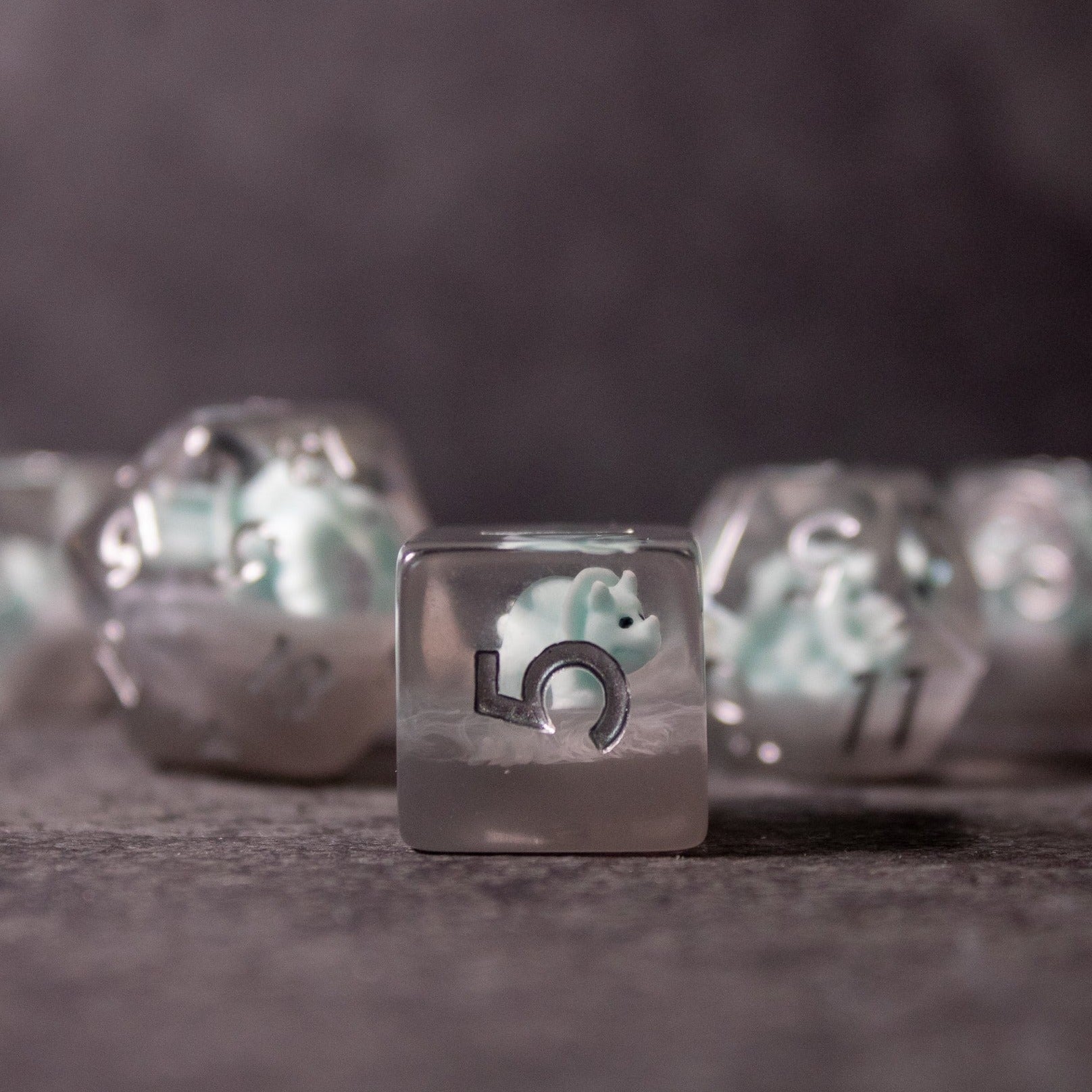 Dinosaur Dice Set - Triceratops - Clear resin dice with embedded light blue and white Triceratops dinosaur figures and black numbering.