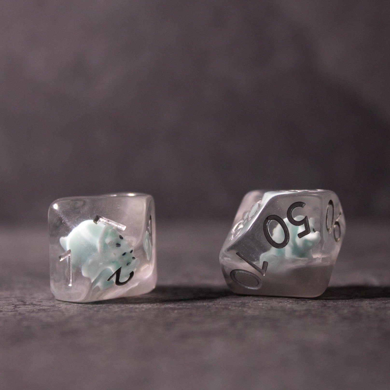 Dinosaur Dice Set - Triceratops - Clear polyhedral dice with small mint green triceratops figures inside and silver numbers.