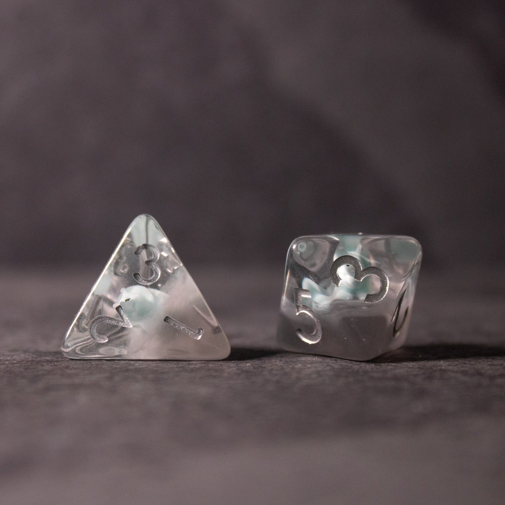 Dinosaur Dice Set - Triceratops - Clear polyhedral dice set with embedded miniature white triceratops figures, showing a four-sided and six-sided die.