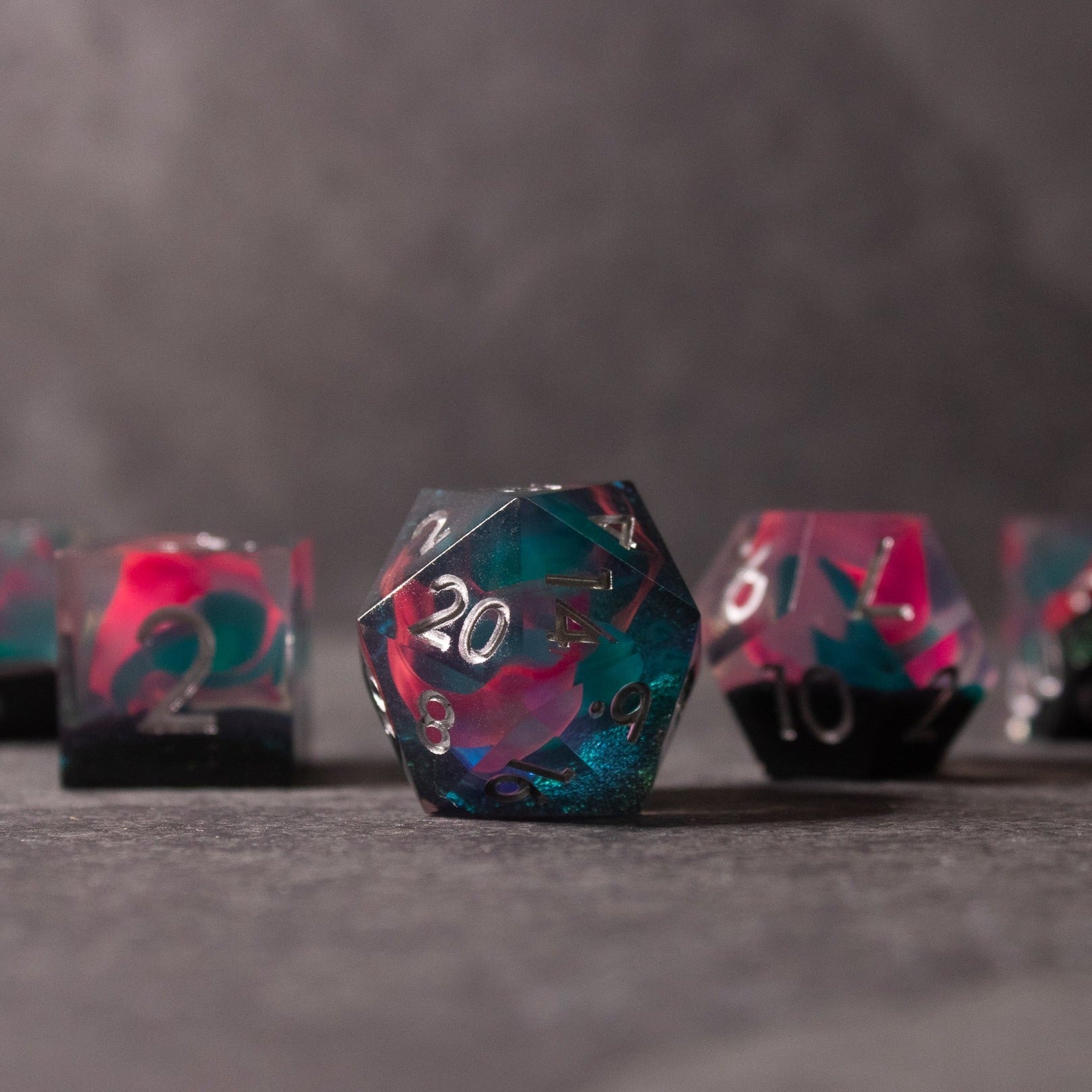 Pink & Green Flame Sharp Edge Dice Set - Sharp-edged 20-sided dice with swirling pink and green colors and white numbers.