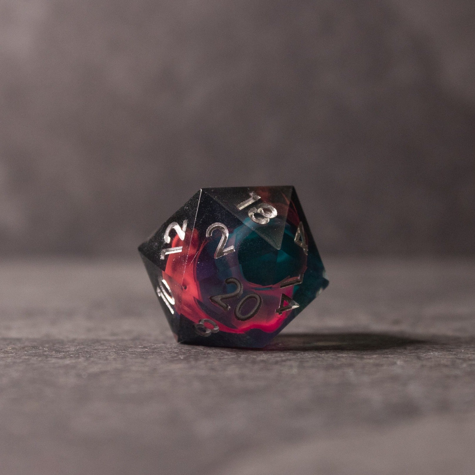 Pink & Green Flame Sharp Edge Dice Set - Sharp-edged d20 dice with swirling pink and green translucent colors on gray surface.