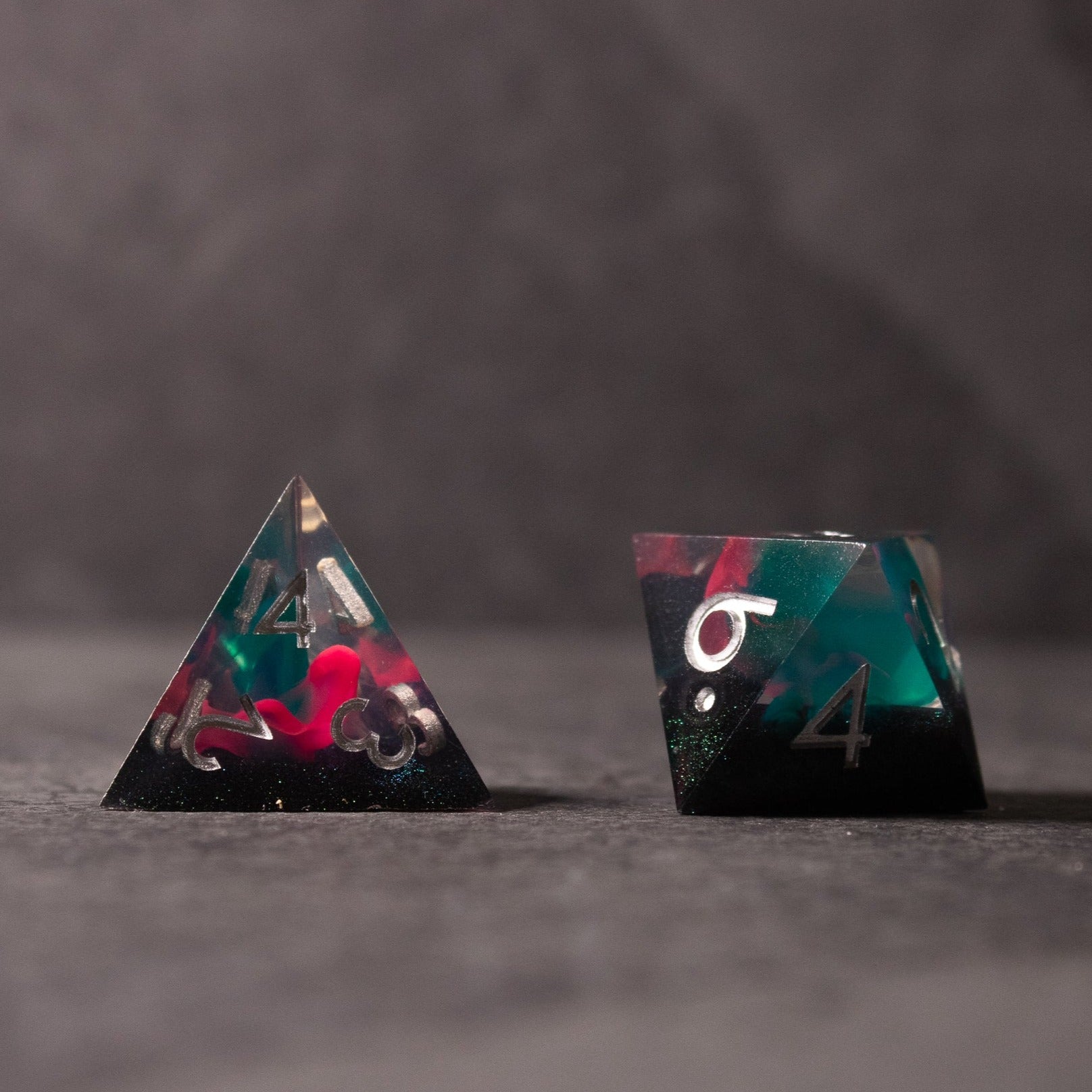 Pink & Green Flame Sharp Edge Dice Set - Pink and green translucent sharp-edged dice with white numbering, including a tetrahedron and a cube-shaped die.