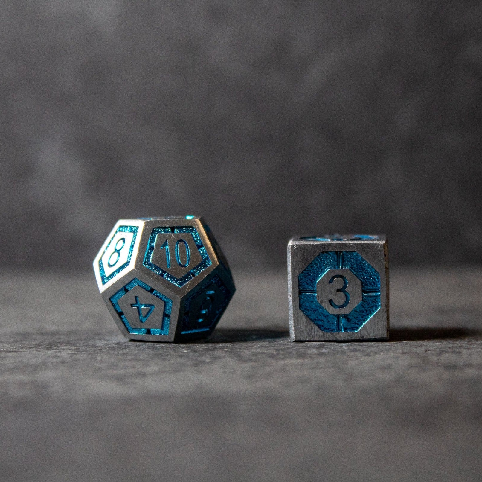 Cobalt Core Metal Dice Set - Blue metal d20 and d6 dice with black edges and engraved numbers on blue faces.