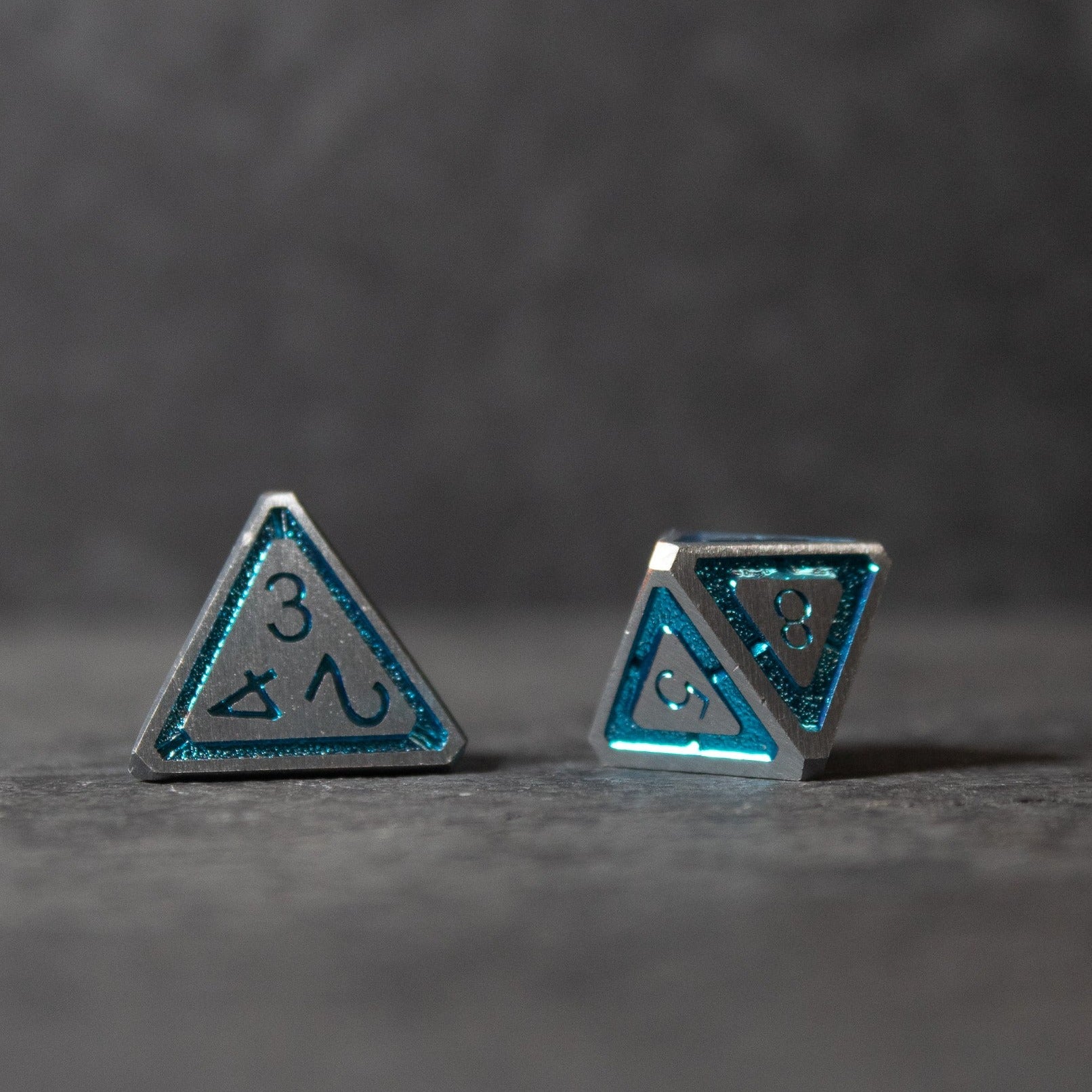 Cobalt Core Metal Dice Set - Blue cobalt metal tetrahedron dice with engraved numbers and symbols.