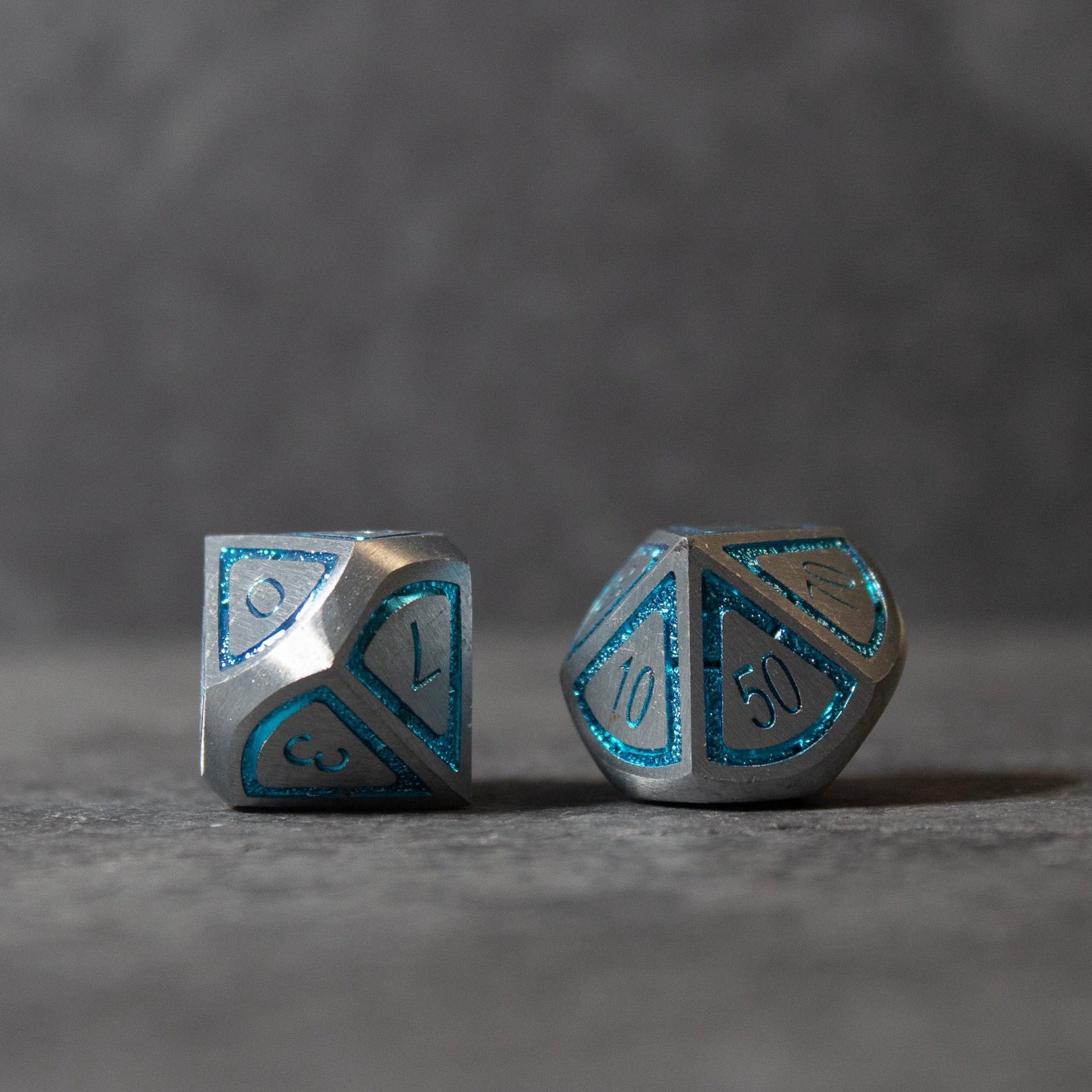 Cobalt Core Metal Dice Set - Metallic dice set with cobalt blue inset numbers, featuring a d8 and d10 with angular geometric shapes.