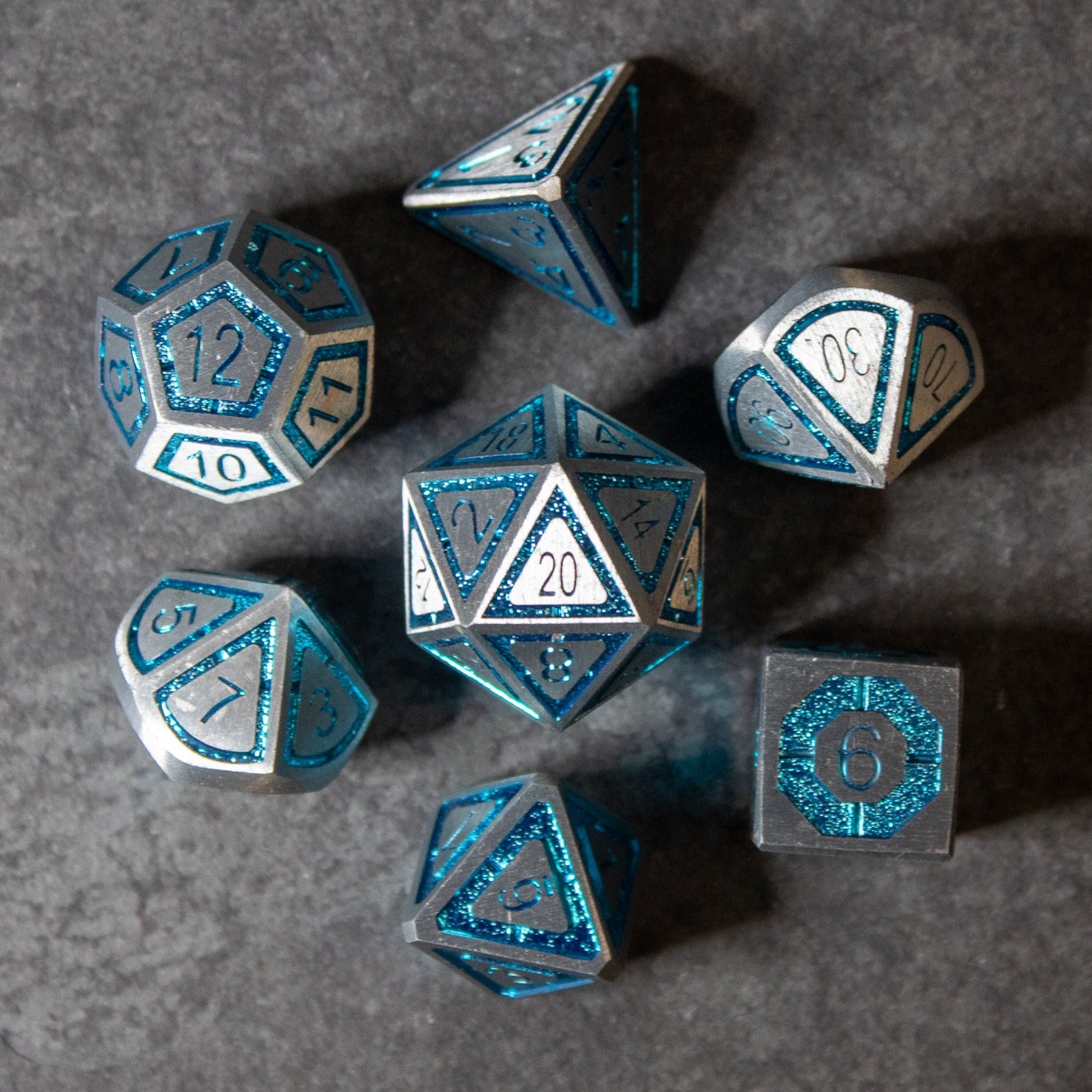 Cobalt Core Metal Dice Set - Set of seven cobalt blue metal polyhedral dice with silver numbering for tabletop gaming and wizards' use.