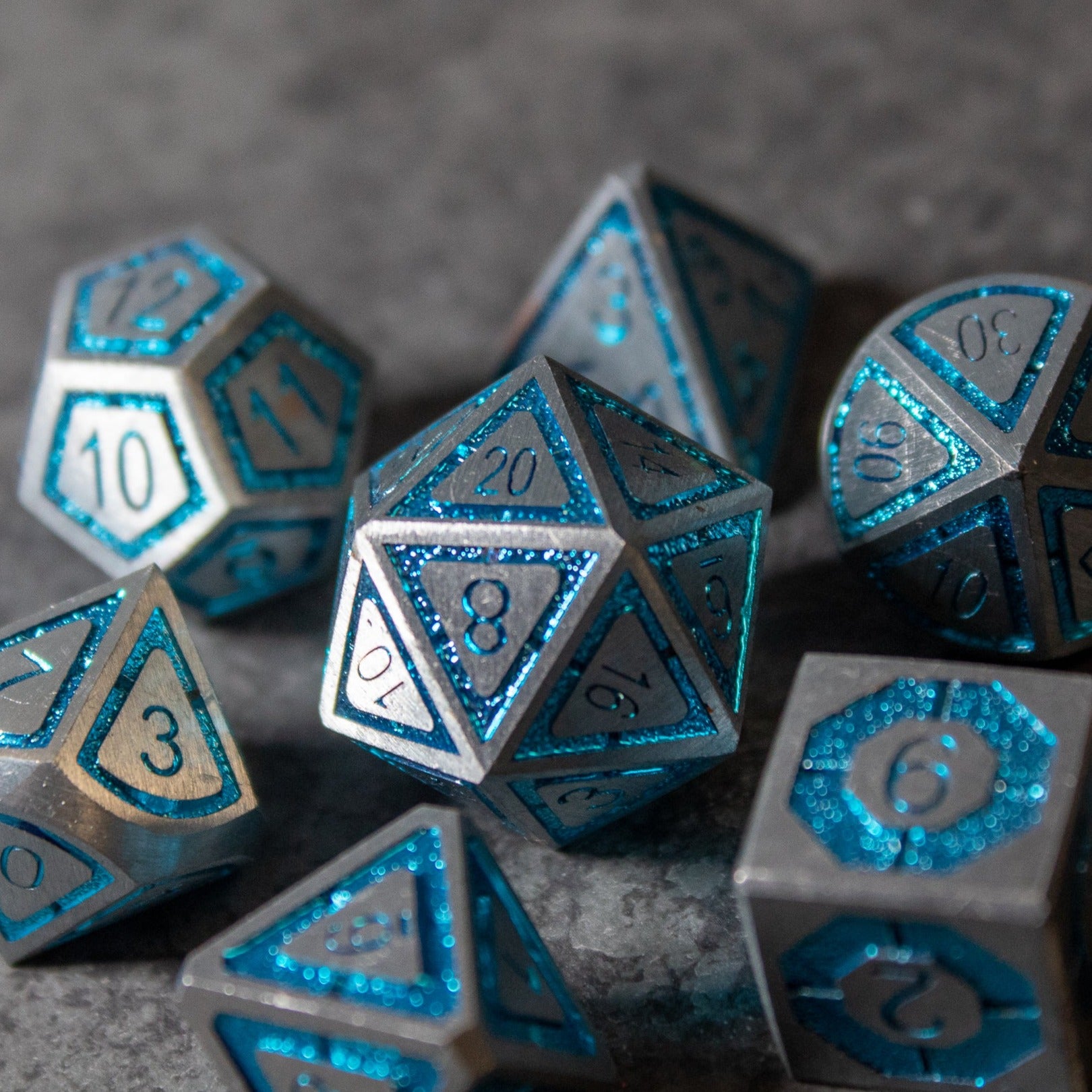 Cobalt Core Metal Dice Set - Set of metal polyhedral dice with a cobalt blue core and silver edges, etched numbers visible.