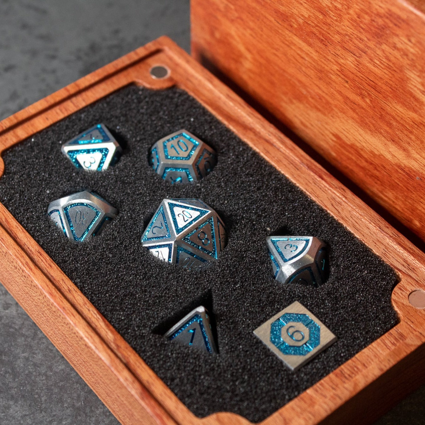 Cobalt Core Metal Dice Set - Cobalt blue metal dice set with silver edges and numbers, displayed in a wooden box with black foam lining.