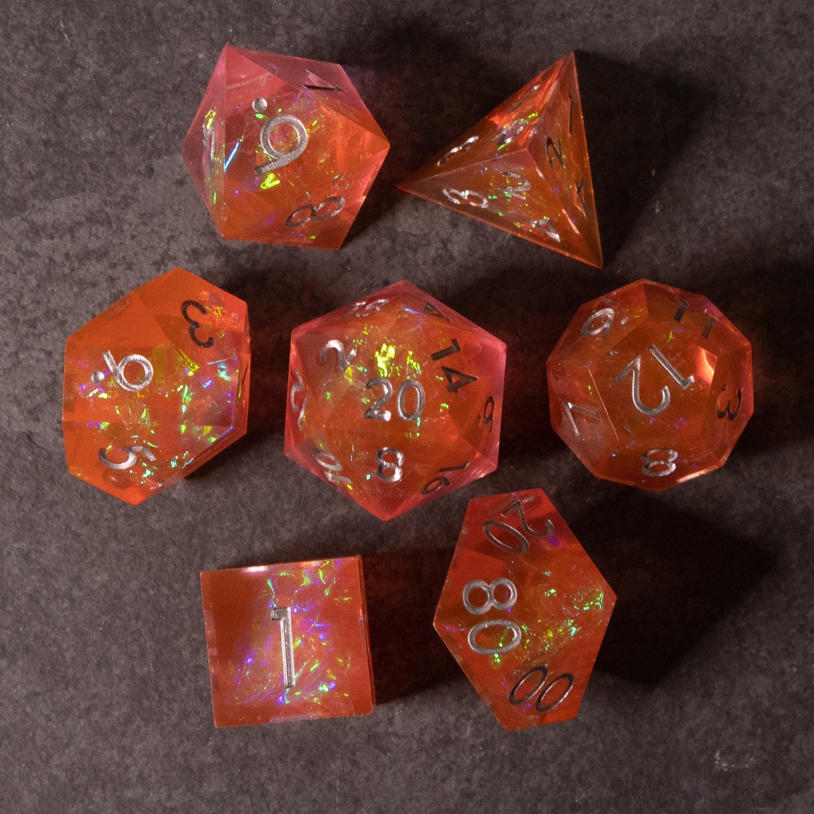 Heart Fire - Opalescent Sharp Edge Dice Set - Translucent red opalescent sharp edge seven-piece polyhedral dice set with gold numbers on dark surface.