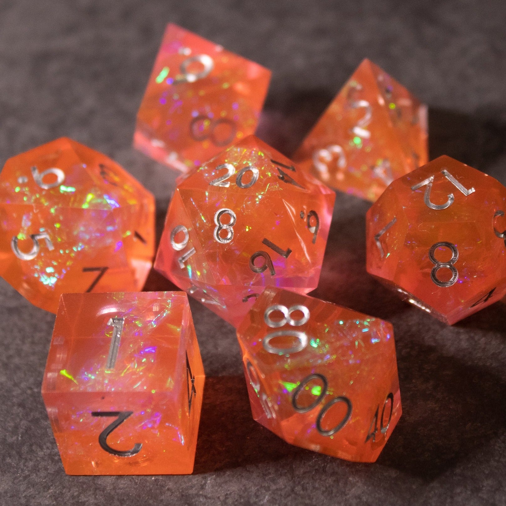 Heart Fire - Opalescent Sharp Edge Dice Set - Set of seven sharp-edged dice in translucent fiery orange with opalescent shimmer and black numbering.