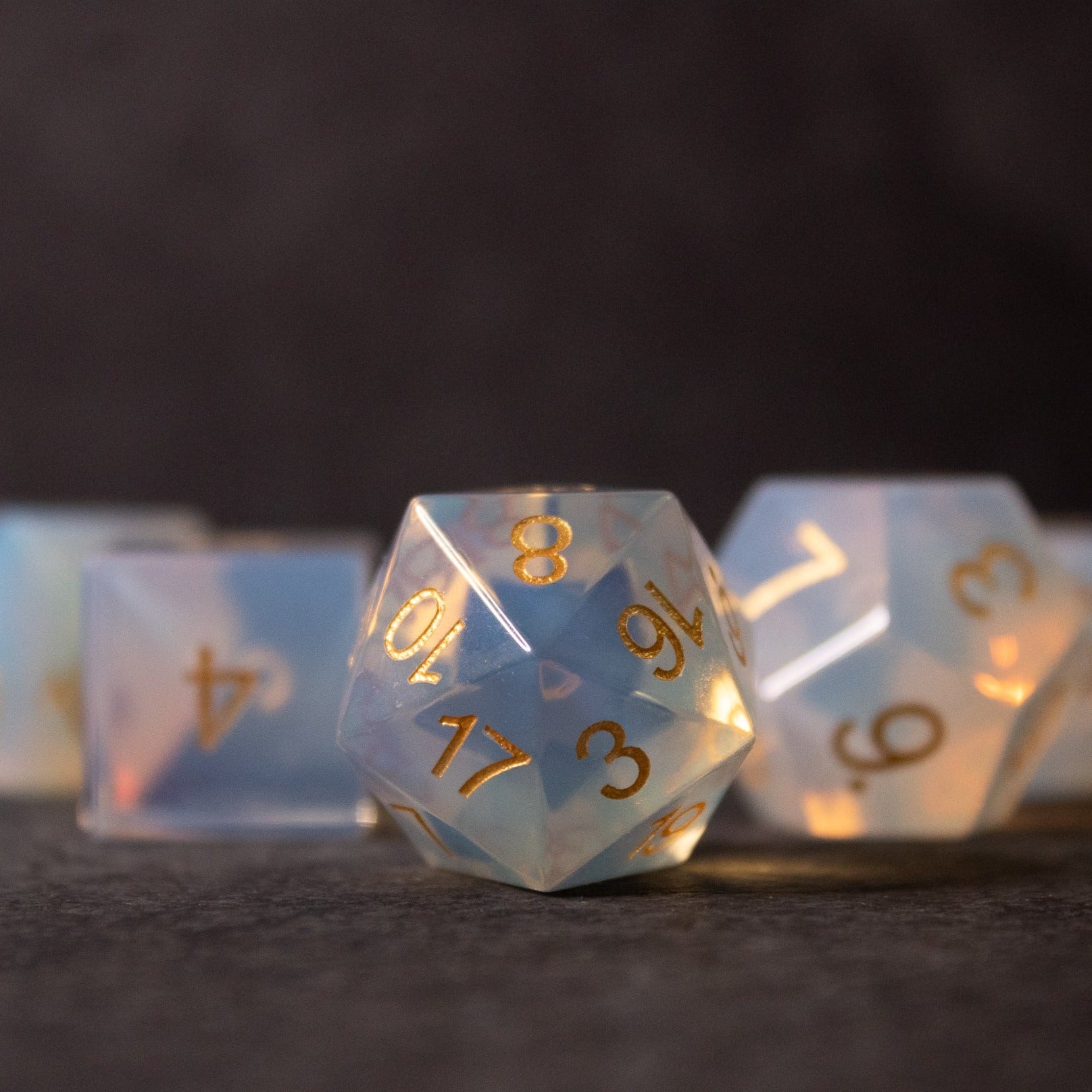 Opalite Gemstone Dice Set - Translucent opalite gemstone dice with gold numbering, featuring a d20 and other polyhedral shapes.