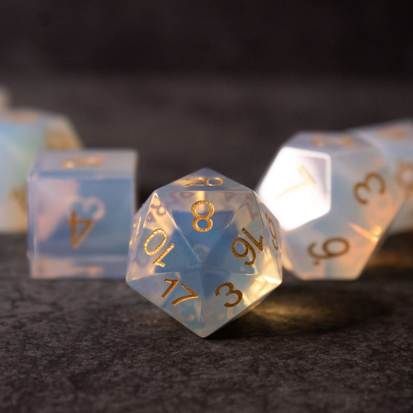 Opalite Gemstone Dice Set - Opalite gemstone dice set with gold numbers, including a d20, d6, and d10, on dark textured surface.