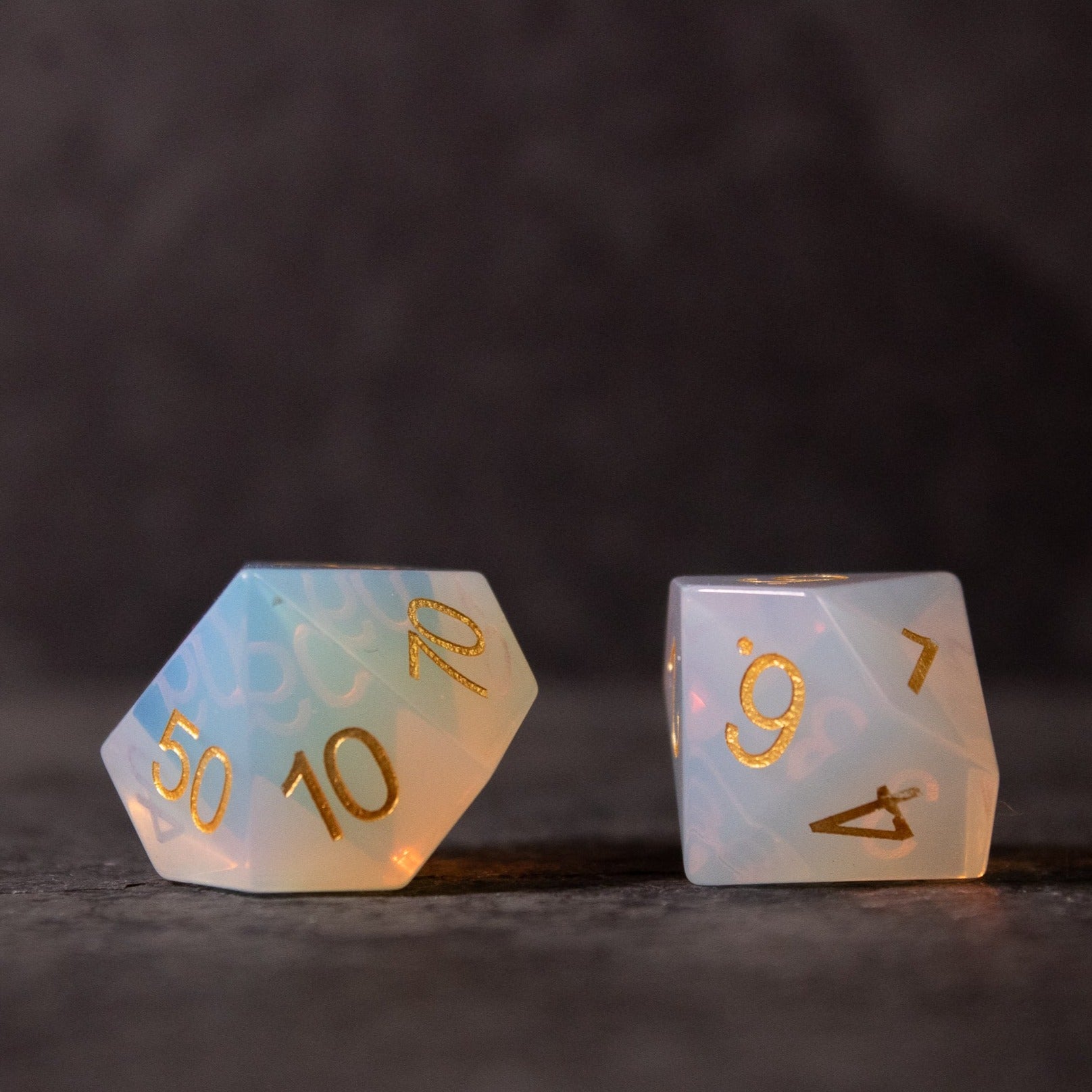 Opalite Gemstone Dice Set - Translucent opalite gemstone dice with gold numbering, one showing 10 and 50, the other showing 9 and 4.