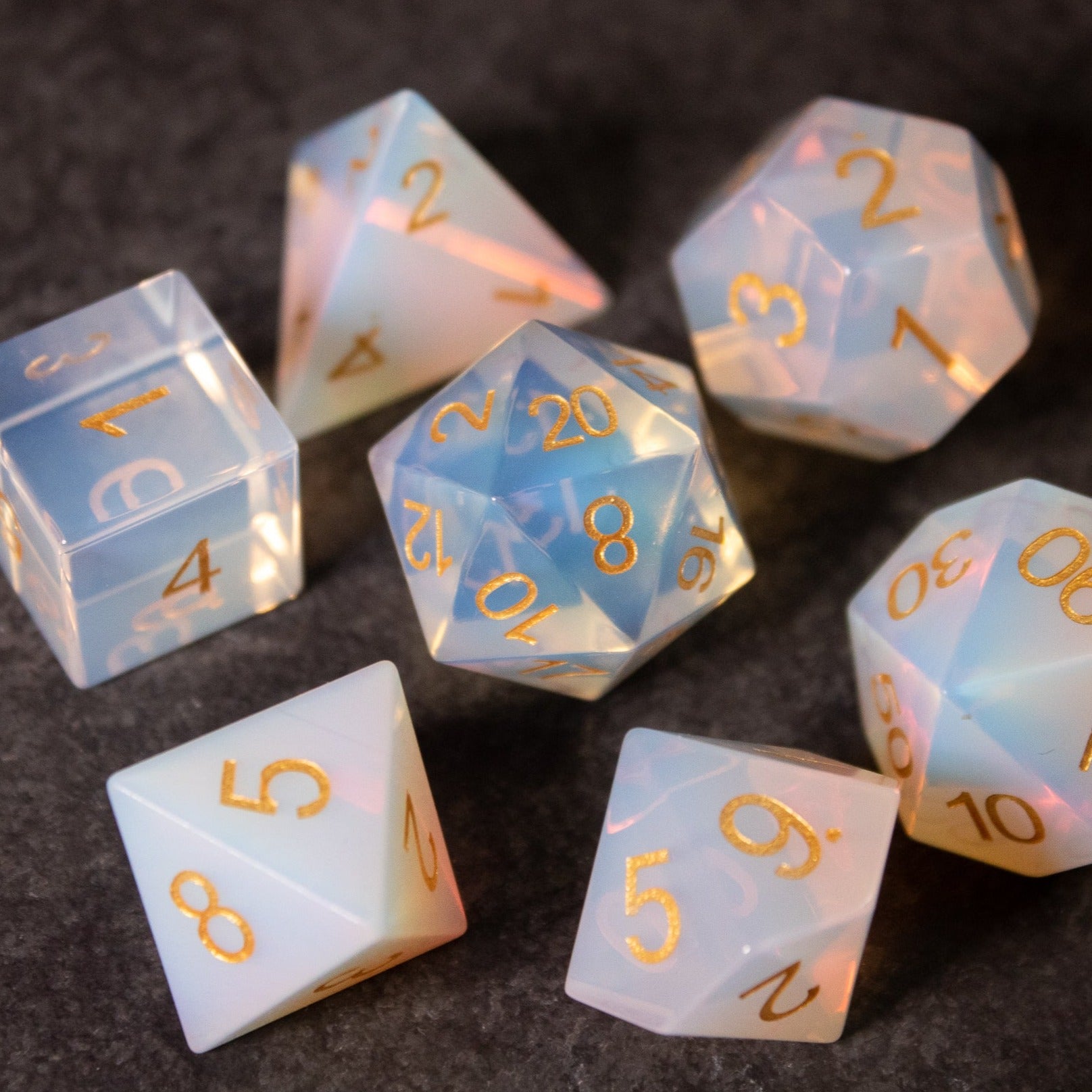 Opalite Gemstone Dice Set - Translucent opalite gemstone dice set with gold numbering, including d4, d6, d8, d10, d12, and d20 shapes.