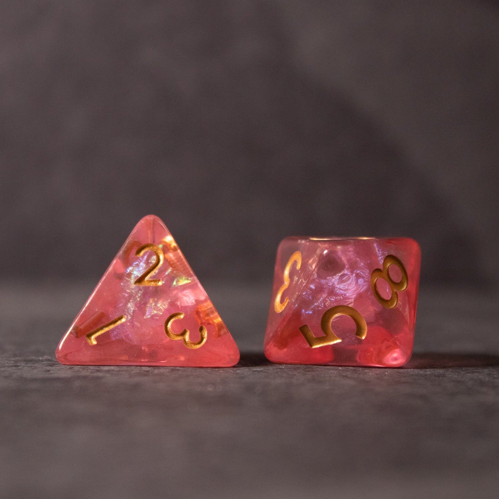 Pink Iridescent Dice Set - Pink iridescent four-sided and eight-sided dice with gold numbering and translucent finish.