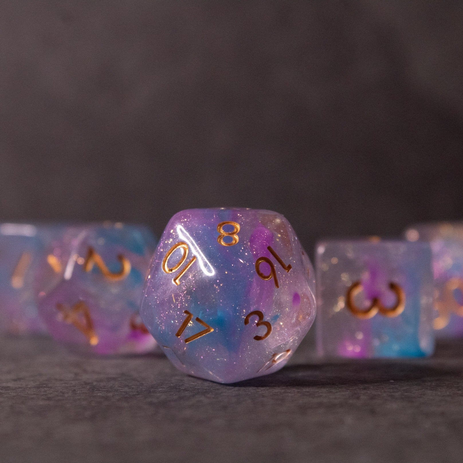 Cotton Candy Dice Set - Purple and pink translucent 20-sided dice with gold numbers from Cotton Candy Dice Set.
