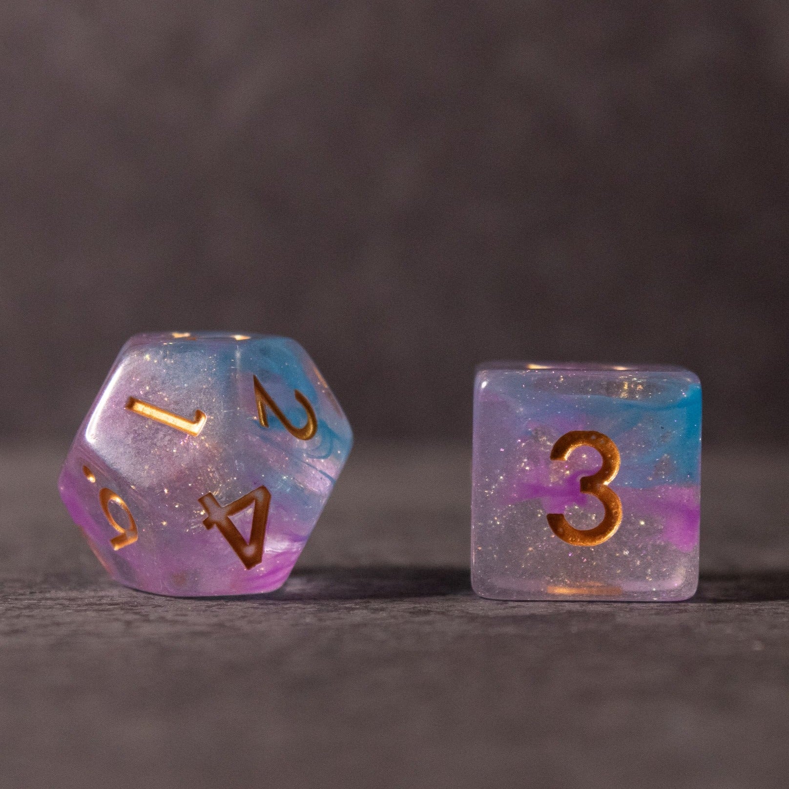 Cotton Candy Dice Set - Translucent blue and pink d20 and d6 dice with gold numbers and a glittery finish.