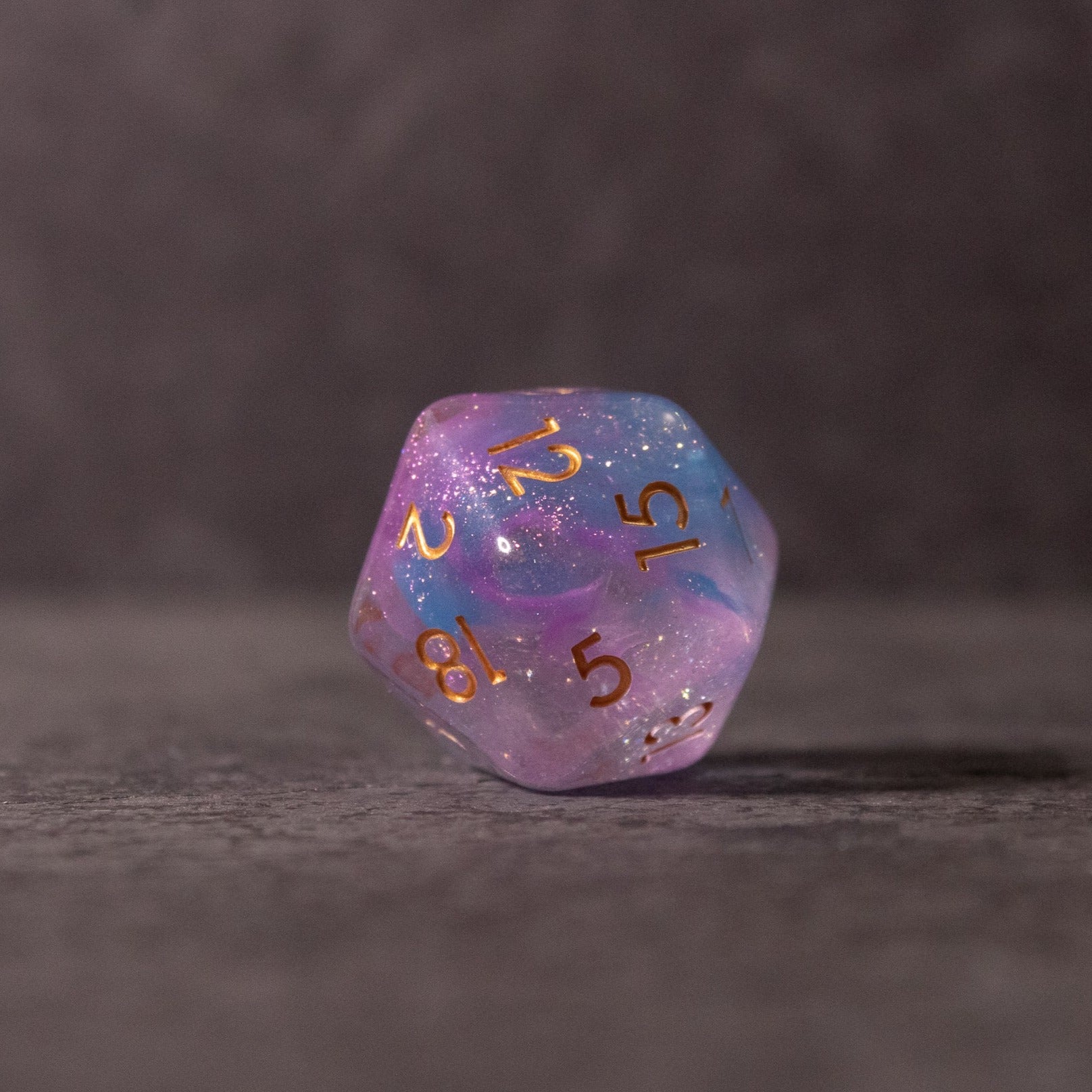 Cotton Candy Dice Set - Translucent 20-sided die with pink and blue swirls and gold numbers.