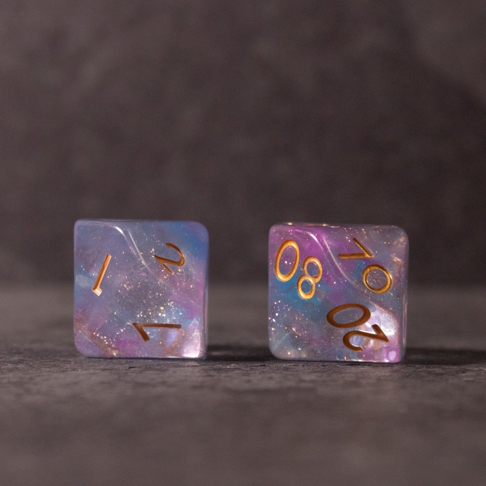 Cotton Candy Dice Set - Two translucent dice with a mix of pastel blue and pink swirls, featuring gold numbers.