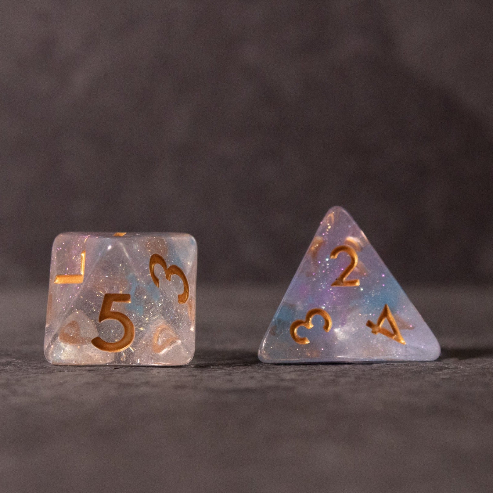 Cotton Candy Dice Set - Translucent pink and blue standard dice set with gold numbers, one six-sided and one four-sided.