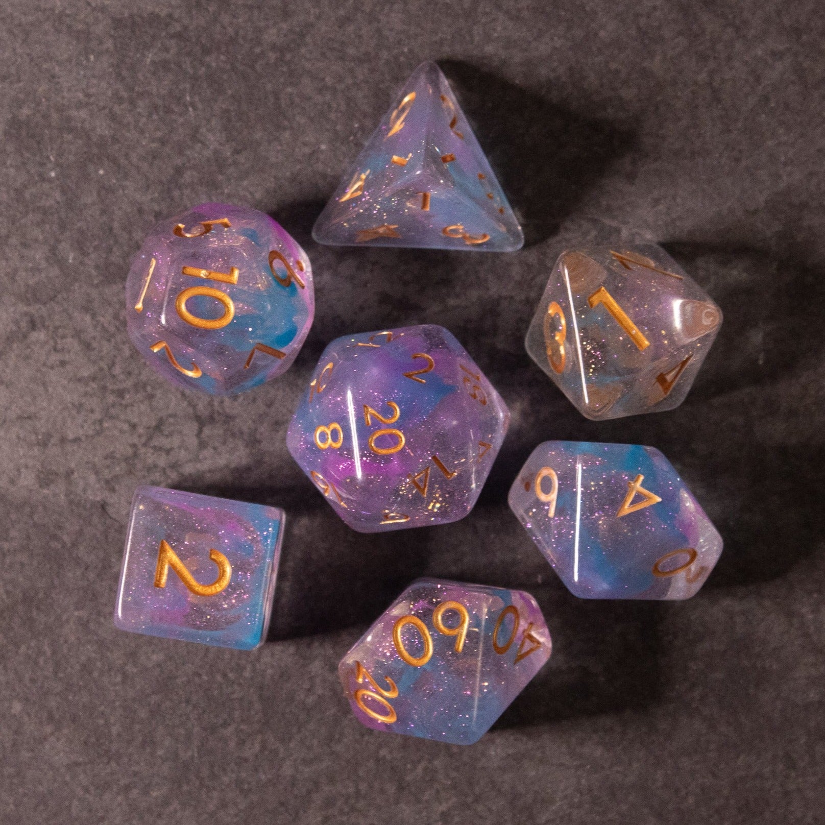 Cotton Candy Dice Set - Translucent purple and pink seven-piece polyhedral dice set with gold numbers, including d4, d6, d8, d10, percentile d10,.
