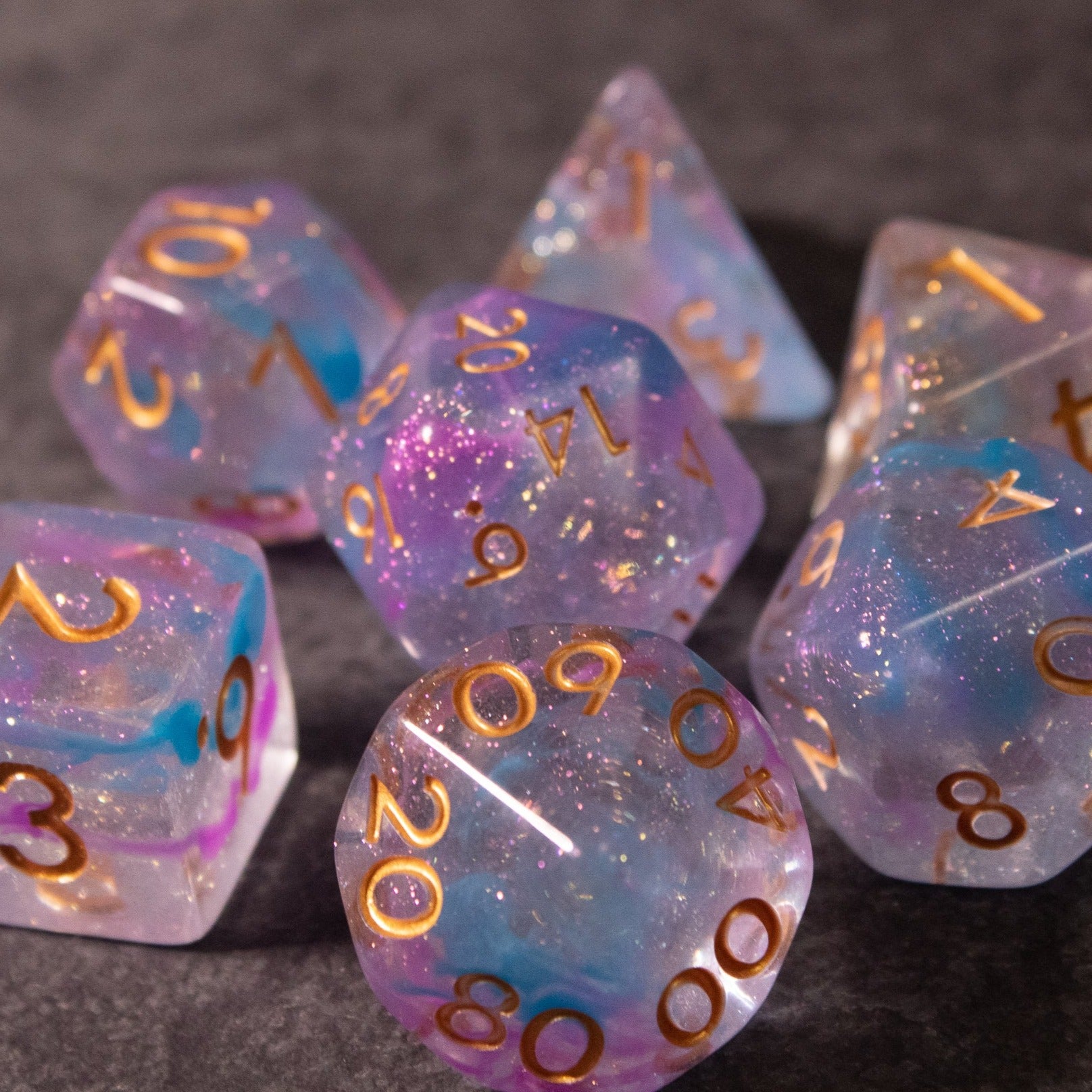 Cotton Candy Dice Set - Set of multicolored translucent dice with blue, pink, and purple swirls and gold numbering.