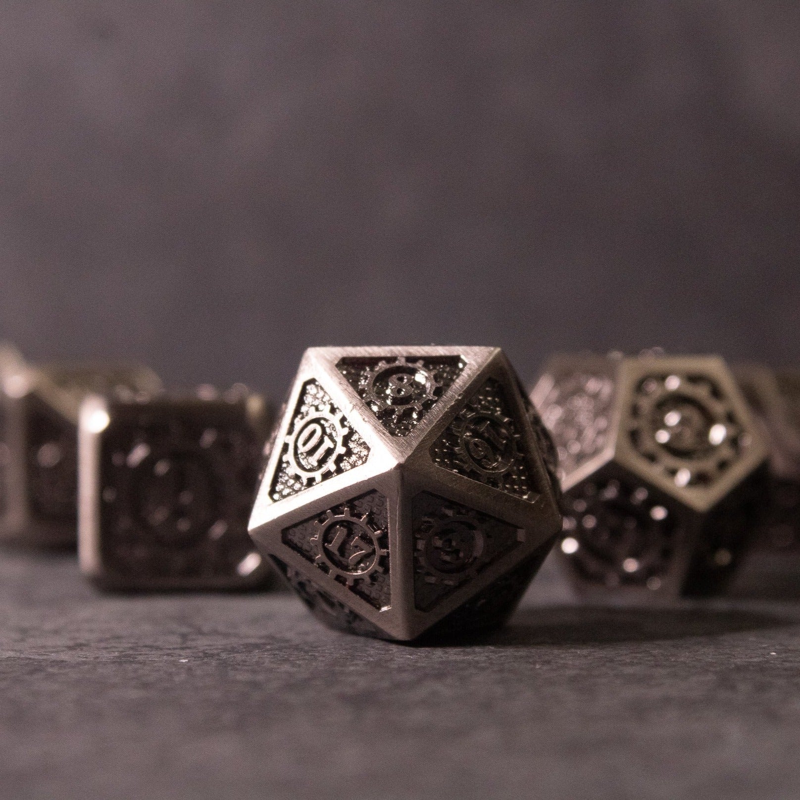 Metal Gear Dice Set - Dark metallic d20 dice with intricate gear-shaped cutouts and textured details.