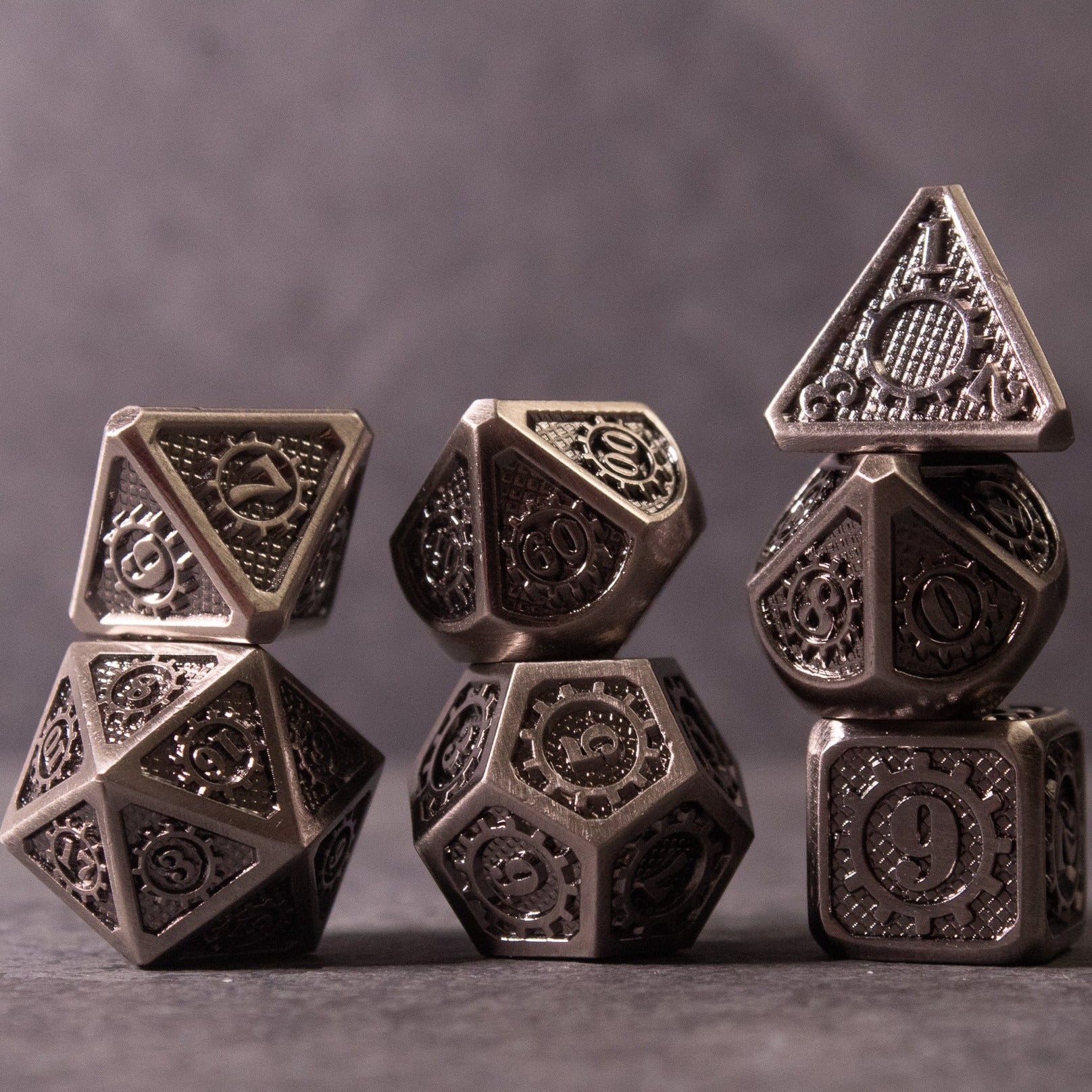 Metal Gear Dice Set - Set of metal dice with intricate gear and cog engravings, featuring dark metallic finish.