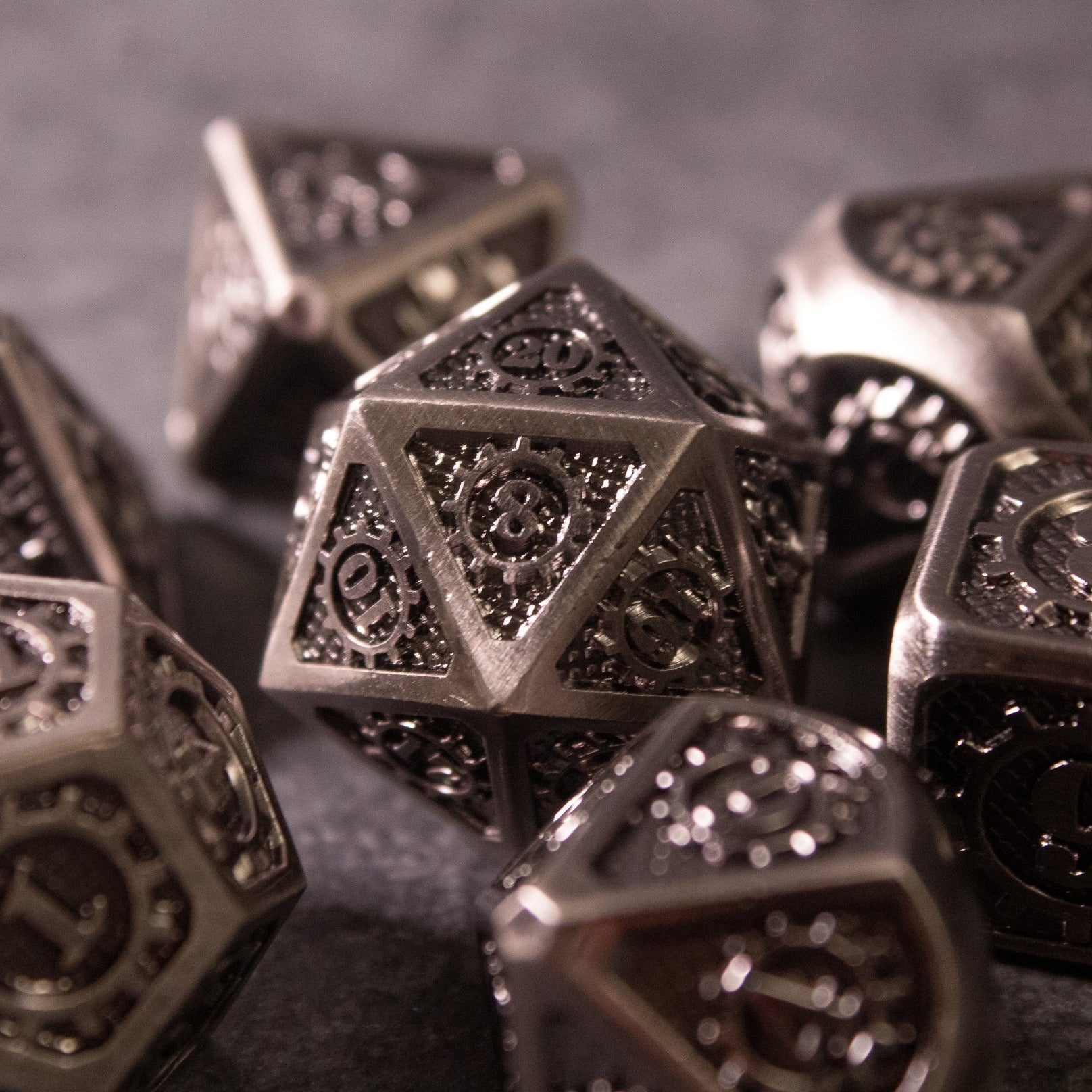 Metal Gear Dice Set - Set of metallic dark gray polyhedral dice with intricate gear and cog engravings on each face.