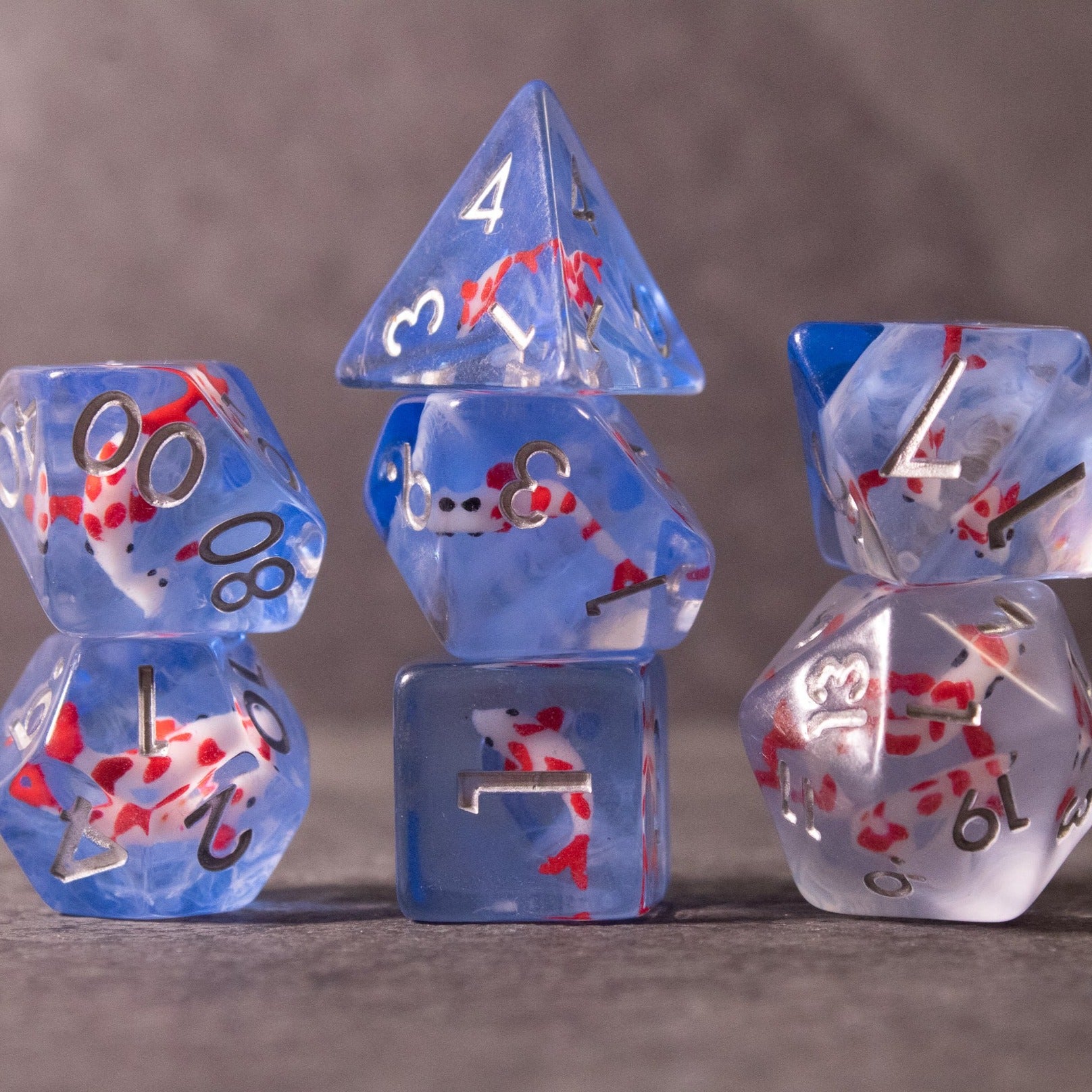 Koi Fish Dice Set - Blue translucent polyhedral dice set with red and white koi fish inclusions and black numbering.