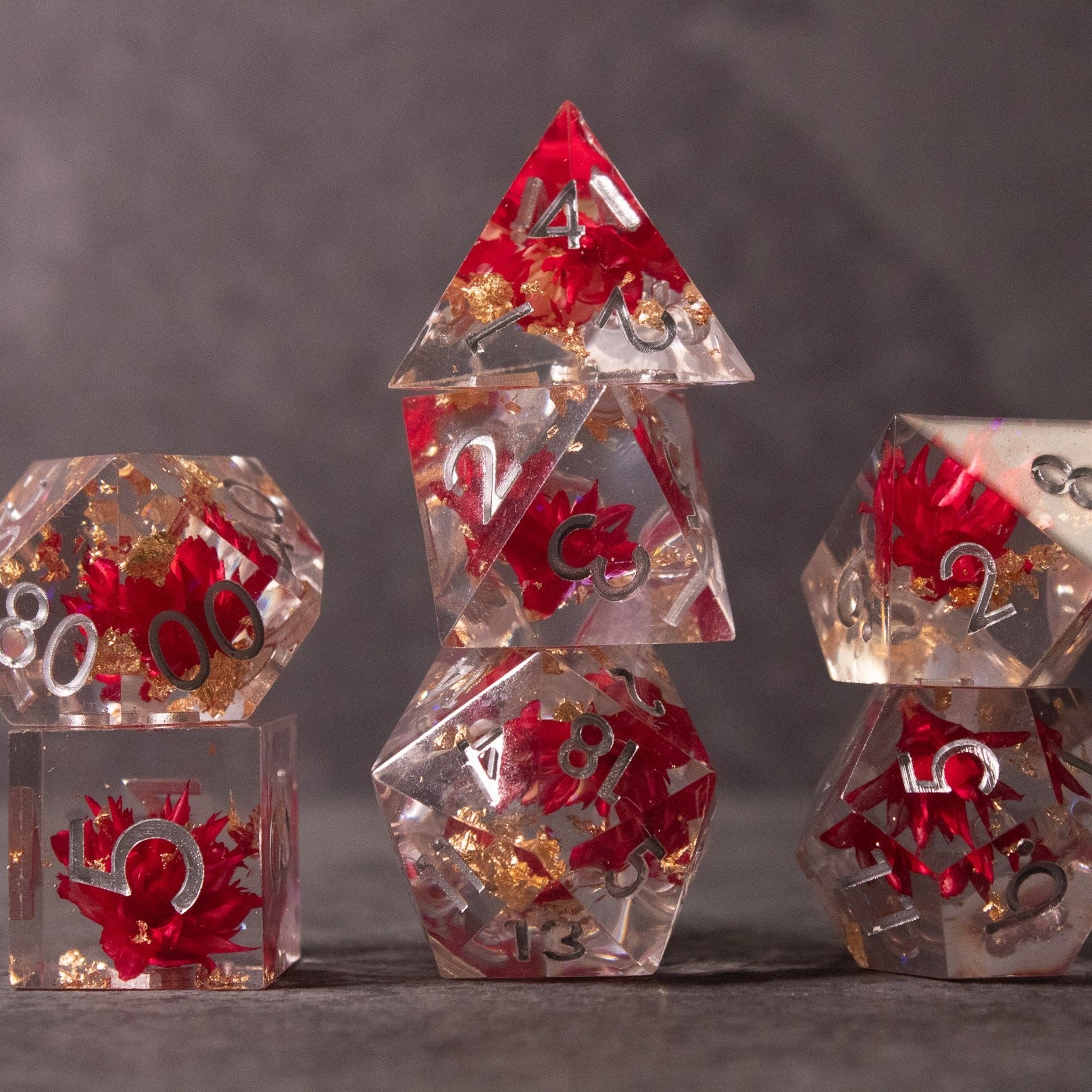 Red Lotus Flower Dice Set - Transparent polyhedral dice set with embedded red lotus flowers and sharp edges, white numbering.
